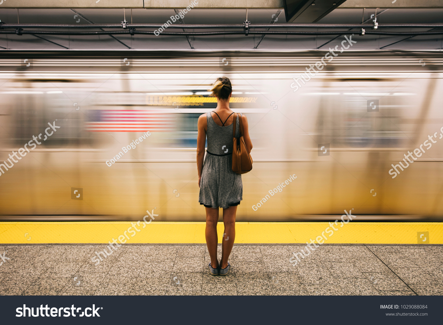 Rear view at young woman waiting for subway train in New York City, USA #1029088084