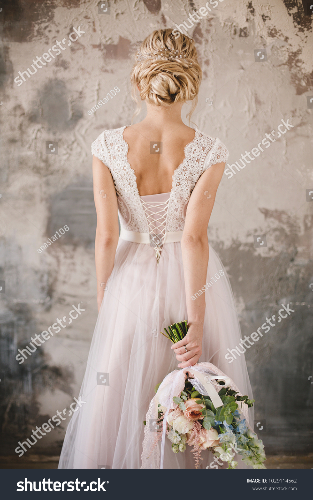 bride's back in lace dress with a bouquet #1029114562