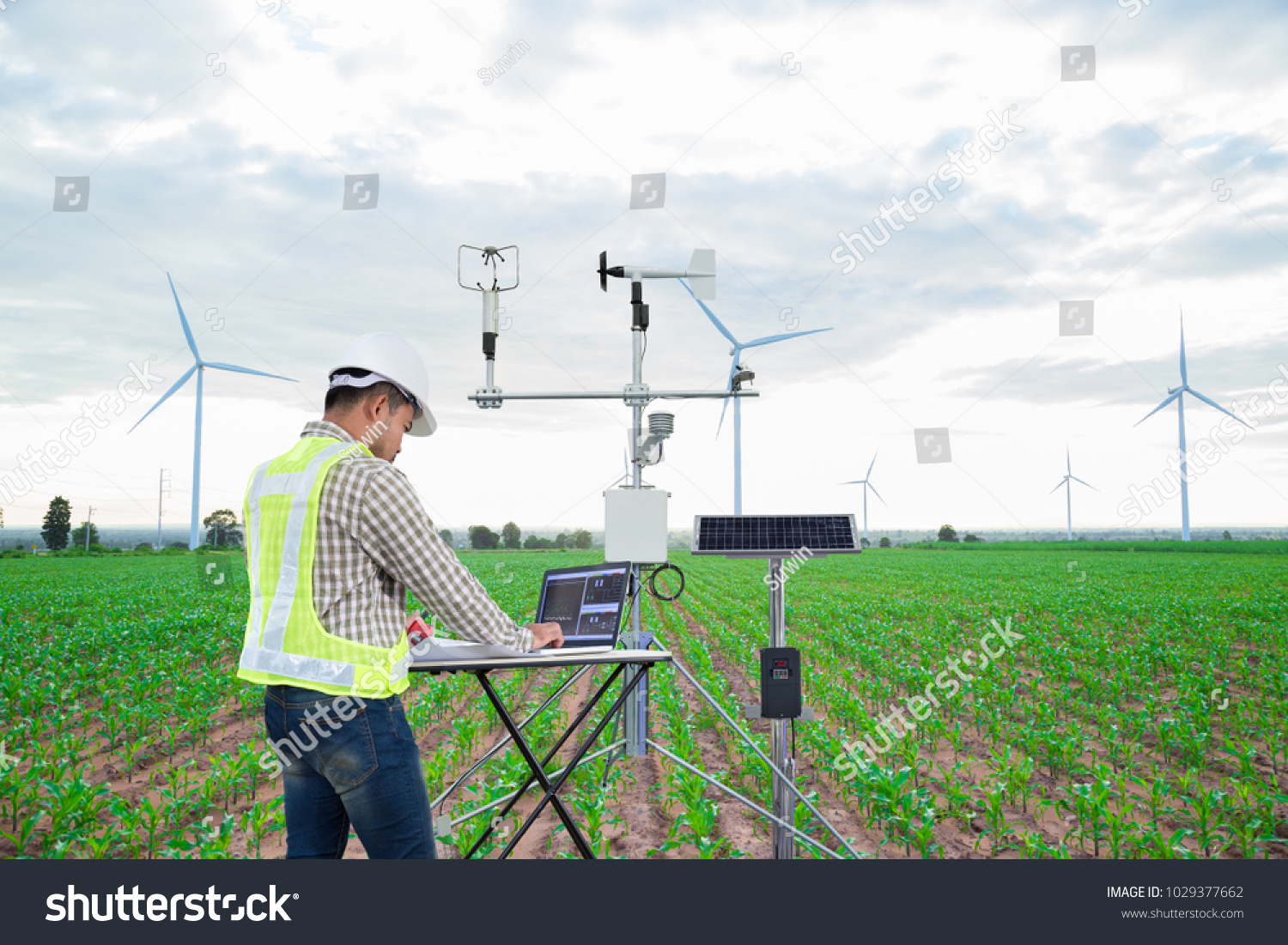Engineer using tablet computer collect data with meteorological instrument to measure the wind speed, temperature and humidity and solar cell system on corn field background, Smart agriculture concept #1029377662