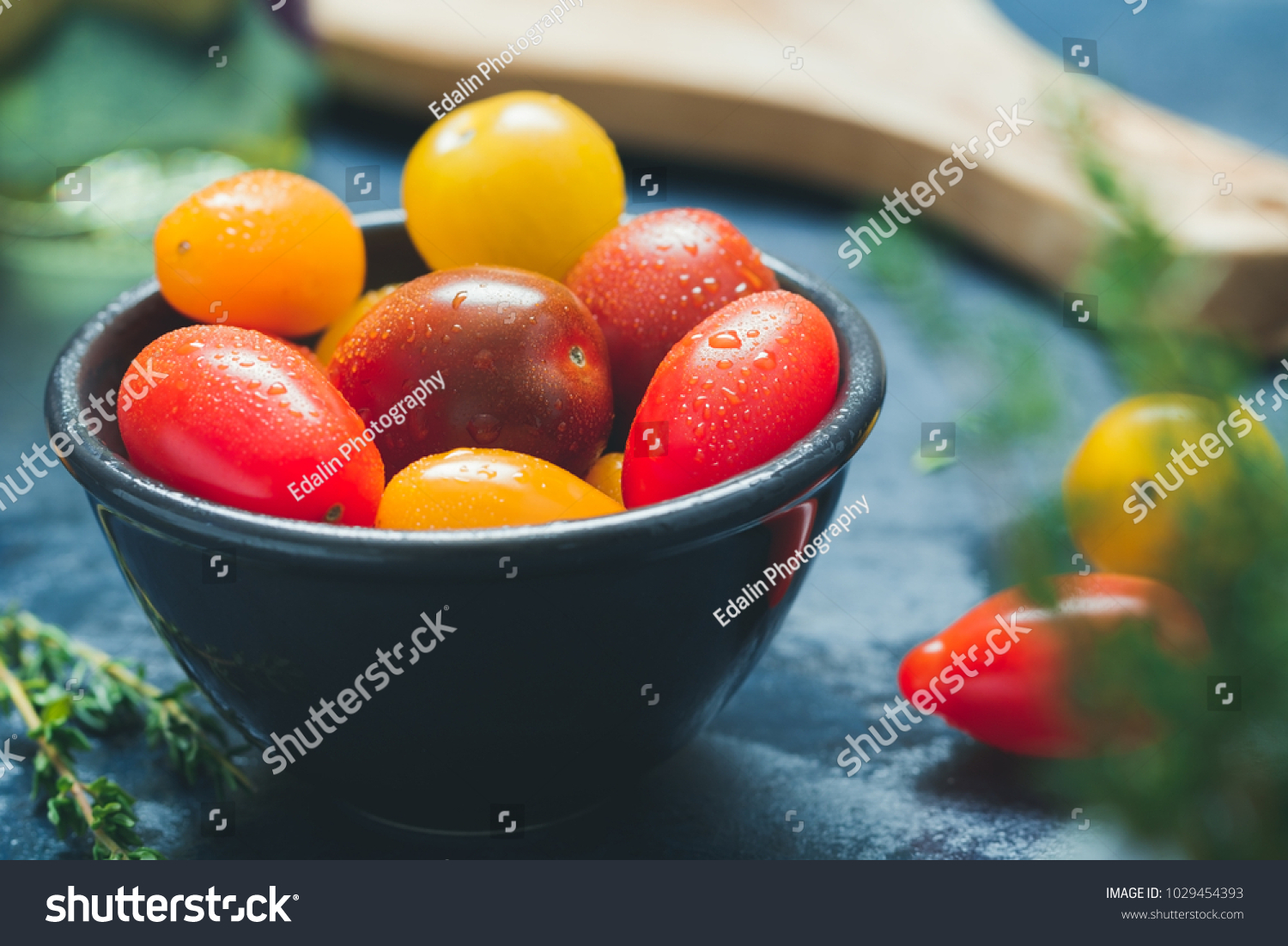 Colorful cherry tomatoes in a black bowl in a kitchen. #1029454393