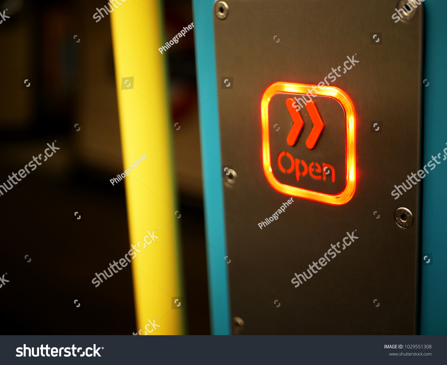 Concept of openness shown by lit 'open' sign with orange chevrons on metropolitan line train on london underground, with yellow pole and view to underground symbol on the platform #1029551308