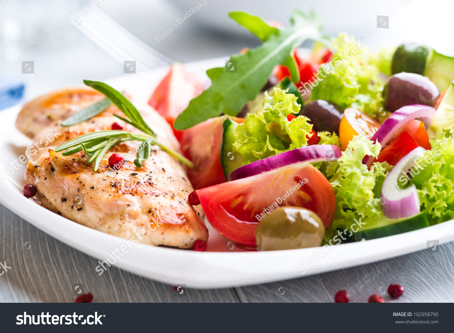 Grilled chicken breast with tomatoes, red pepper, organic green and kalamata olives, red onion, lettuce and fresh rocket and rosemary. Home made food. Concept for a tasty and healthy meal. Close up. #102958790
