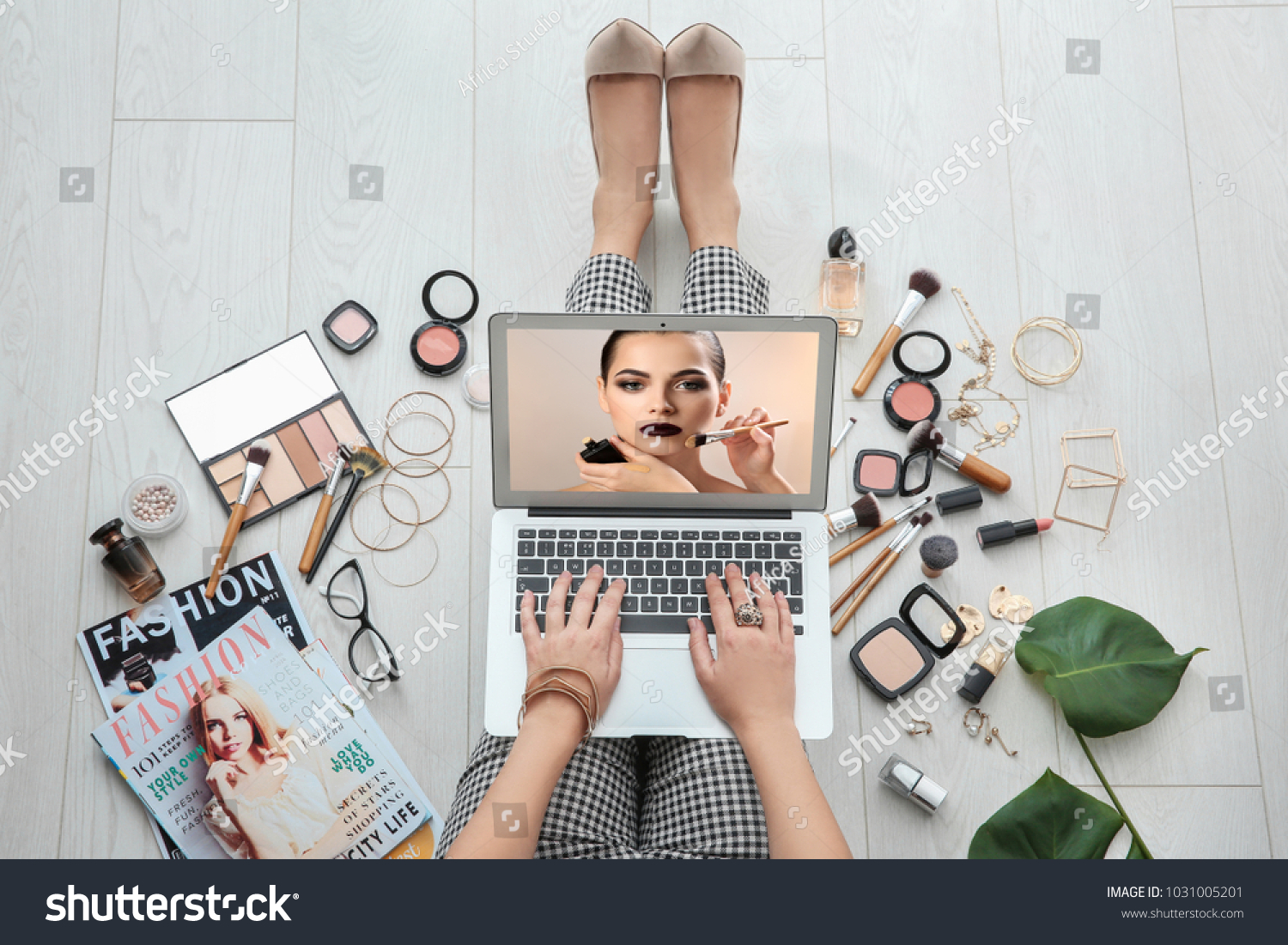 Woman sitting on floor with laptop and watching online training for professional makeup artist #1031005201
