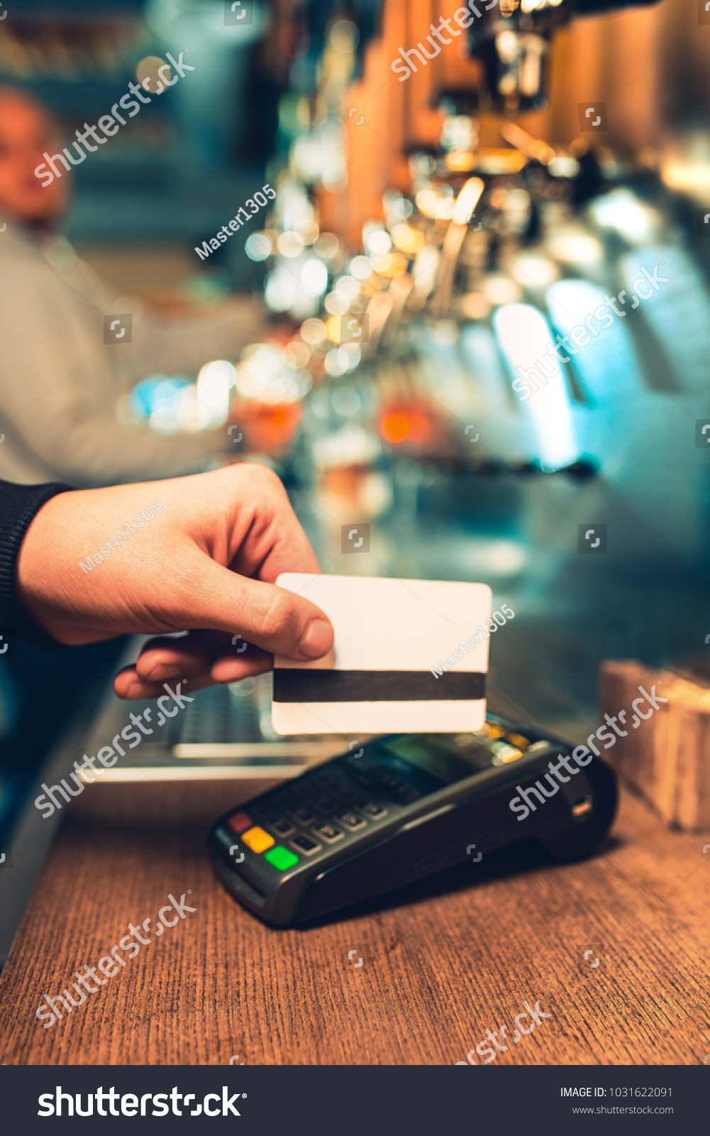Man using payment terminal. White credit card. Hand use credit card. Bar table. The beer taps in a pub. Costumer concept. Service concept. #1031622091