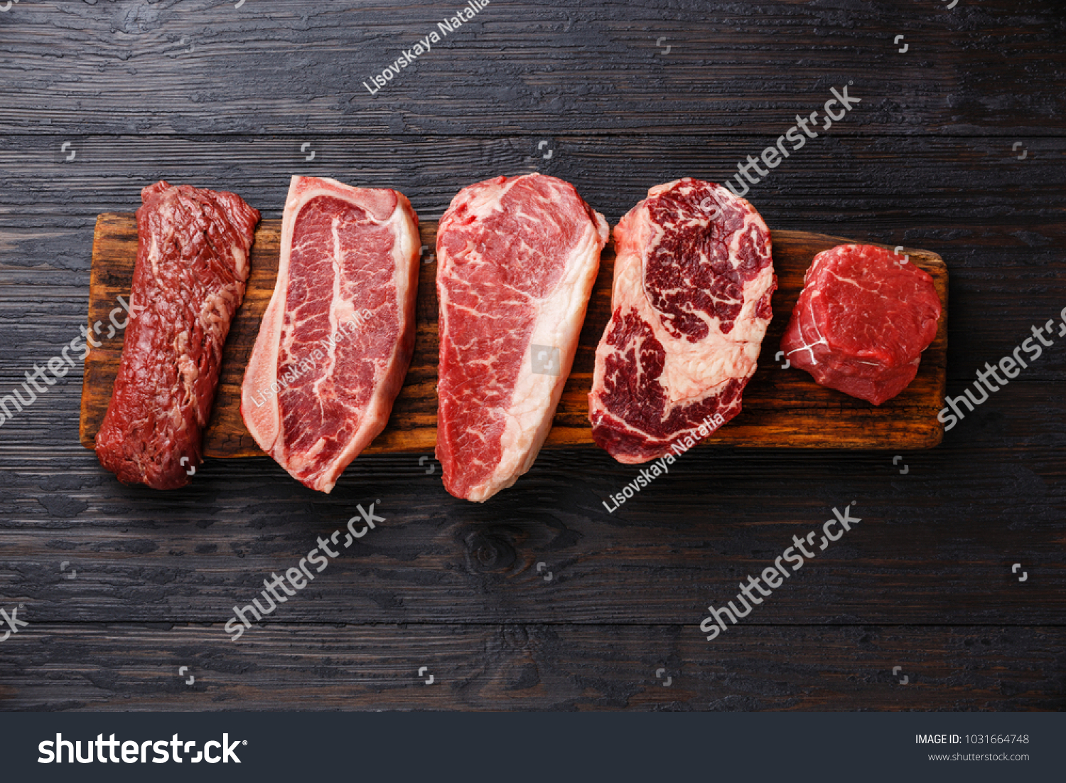 Variety of Raw Black Angus Prime meat steaks Machete, Blade on bone, Striploin, Rib eye, Tenderloin fillet mignon on wooden board copy space #1031664748