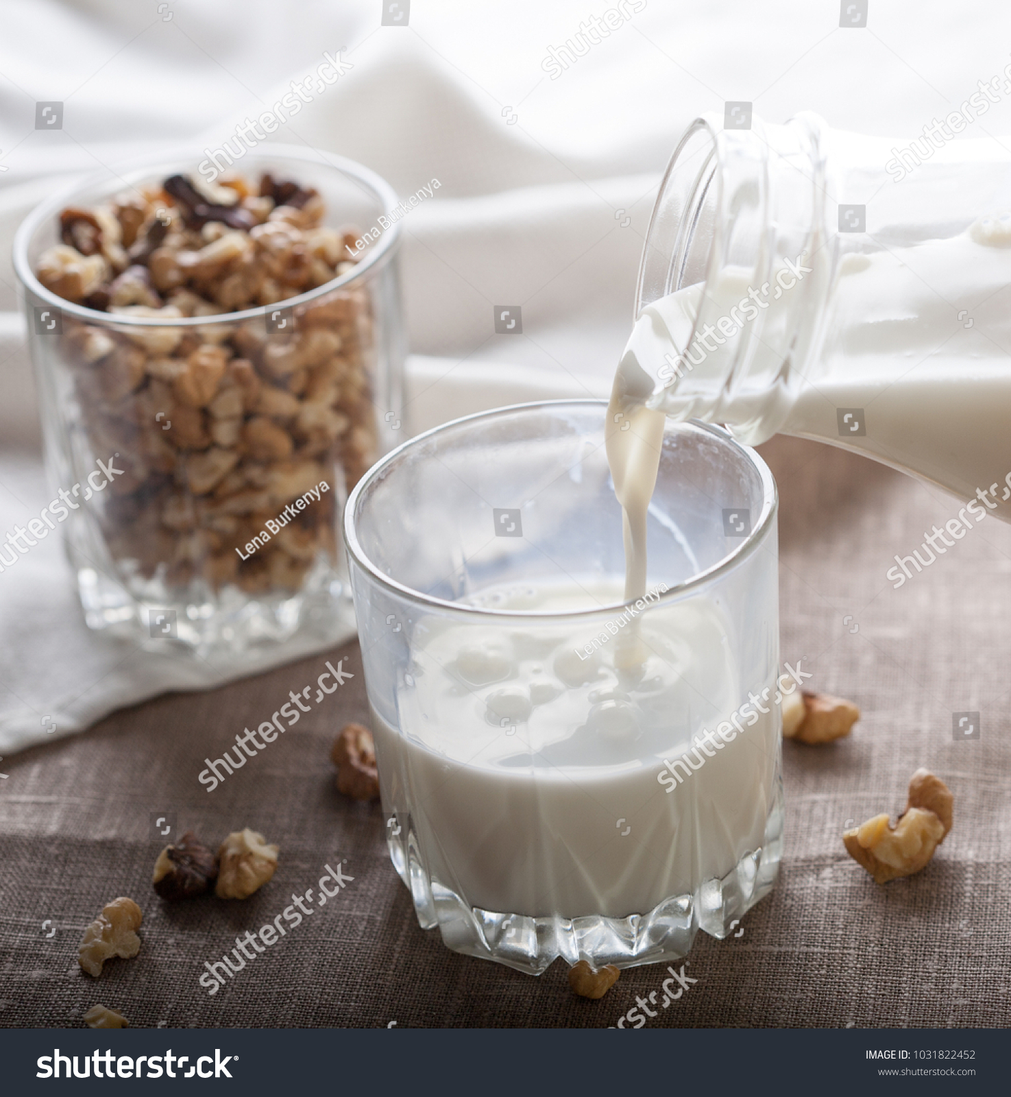 Pouring nut milk from bottle to a glass of milk  #1031822452