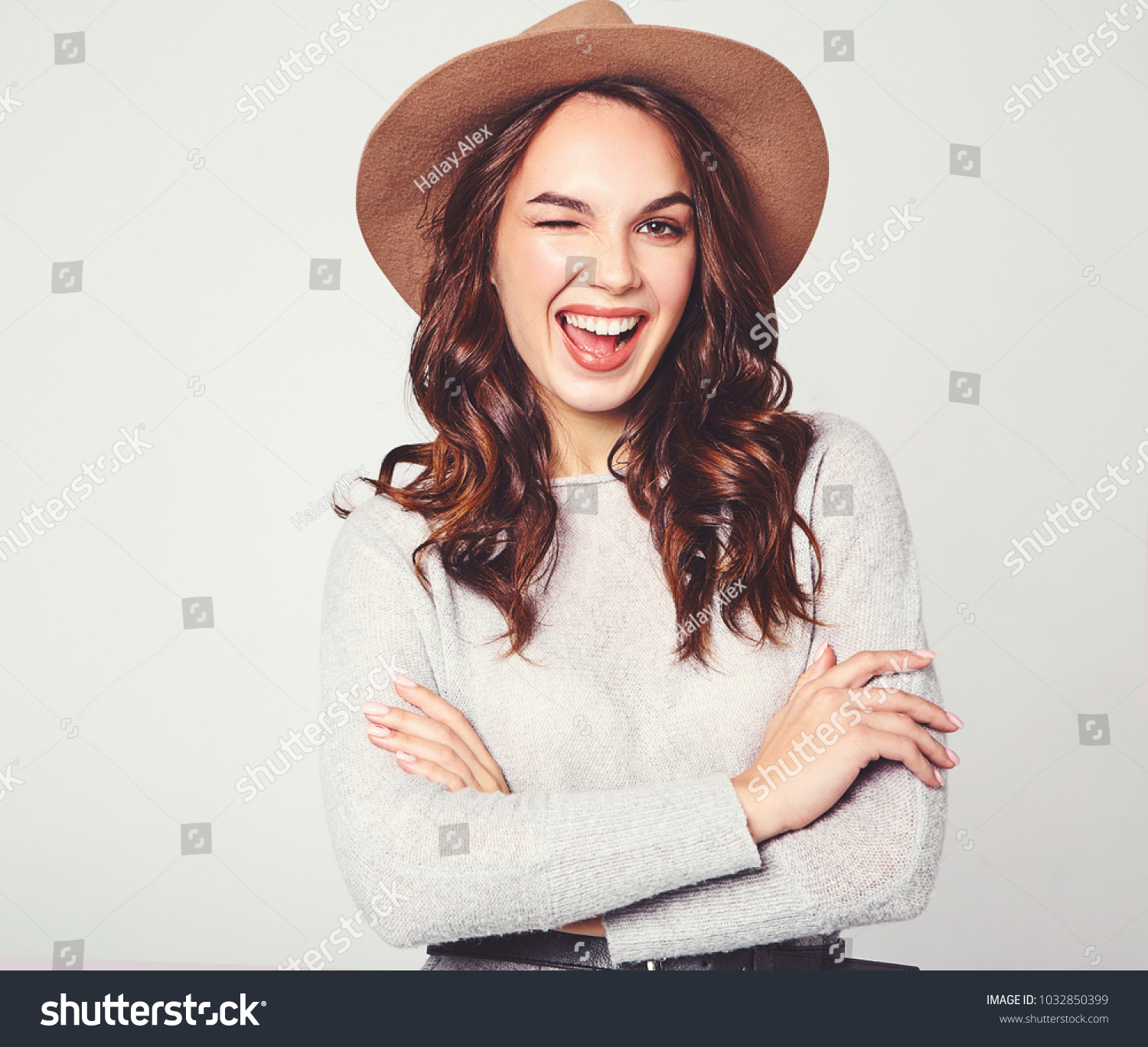 Portrait of young stylish laughing girl model in gray casual summer clothes in brown hat with natural makeup isolated on gray background. Looking at camera and winking #1032850399