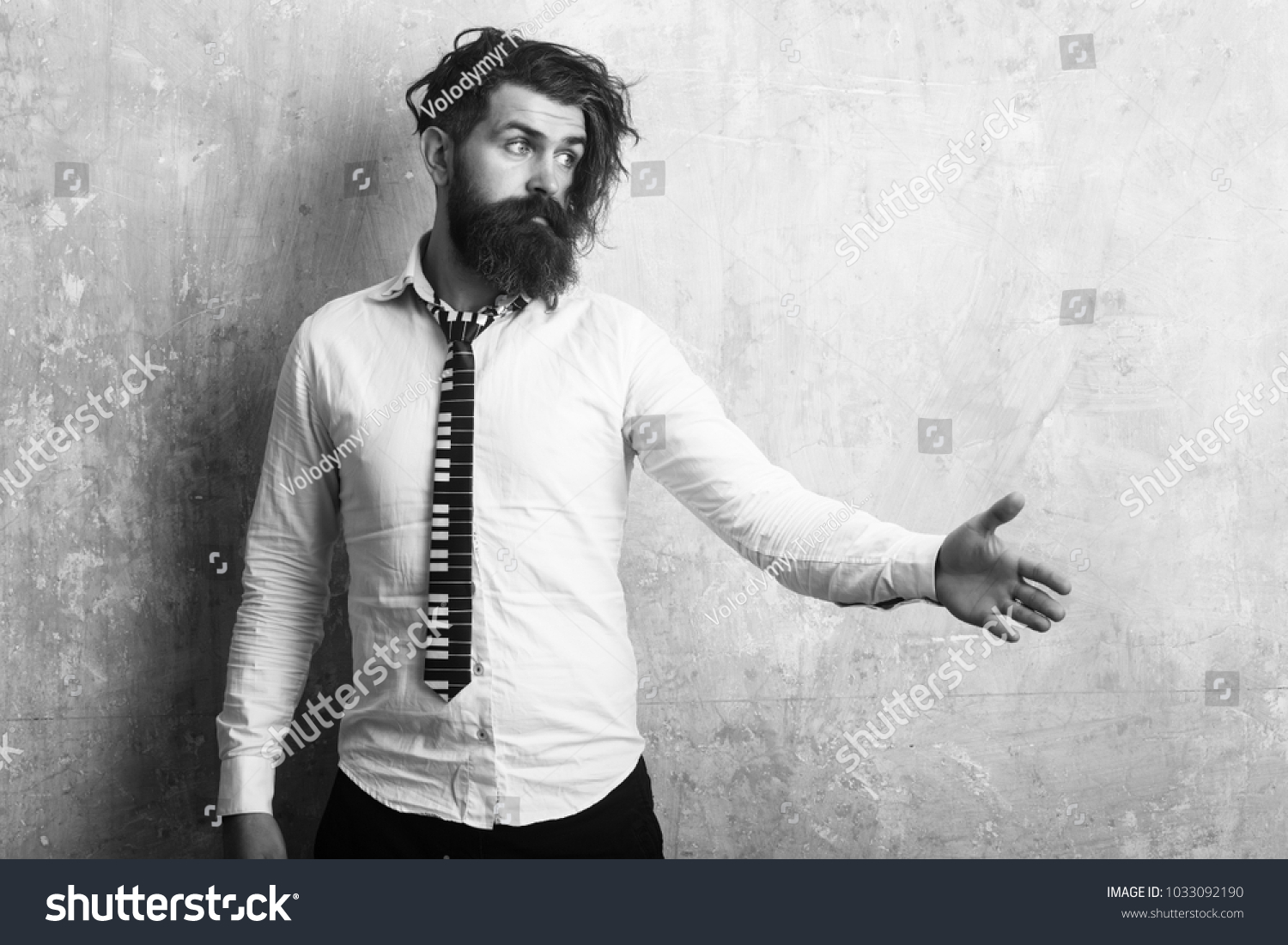 Hipster in shirt and musical tie. Man with long beard and mustache on face. Fashion model with stylish hair on textured wall background Guy hold hand for handshake. Business fashion and beauty. #1033092190