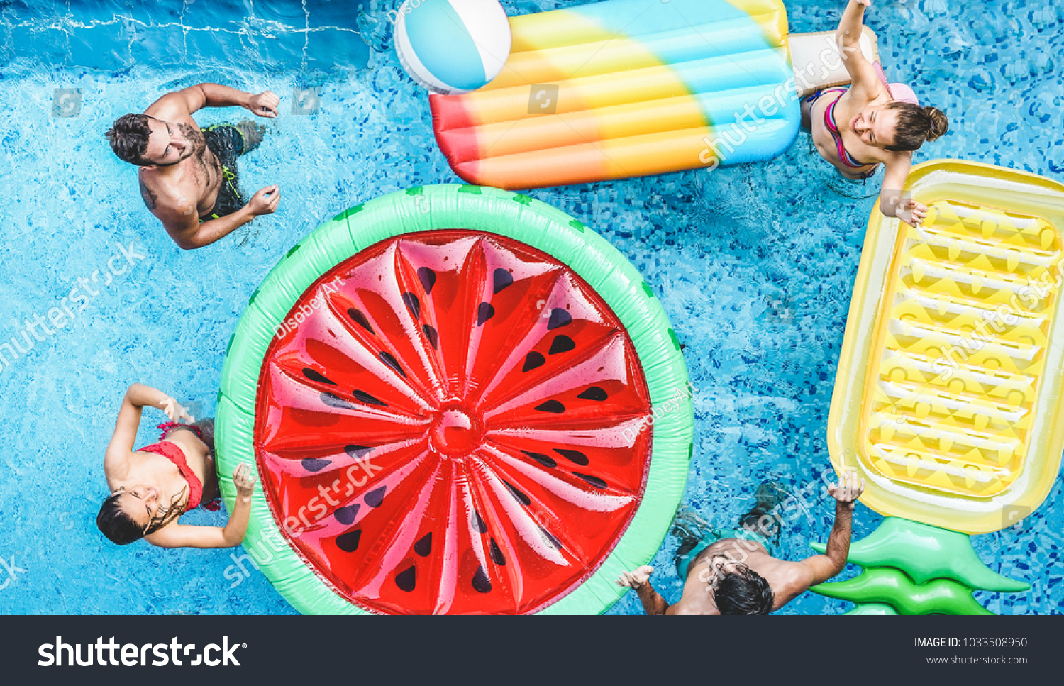 Happy friends playing with air lilo ball inside swimming pool - Young people having fun on summer holidays vacation - Travel, holidays, youth lifestyle, friendship and tropical concept #1033508950