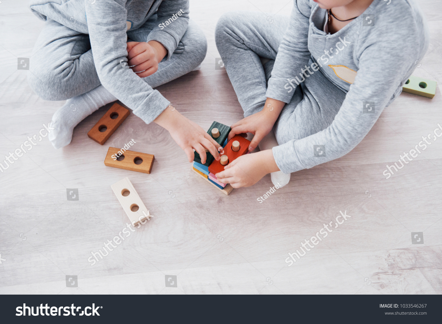 Children play with a toy designer on the floor of the children's room. Two kids playing with colorful blocks. Kindergarten educational games. #1033546267