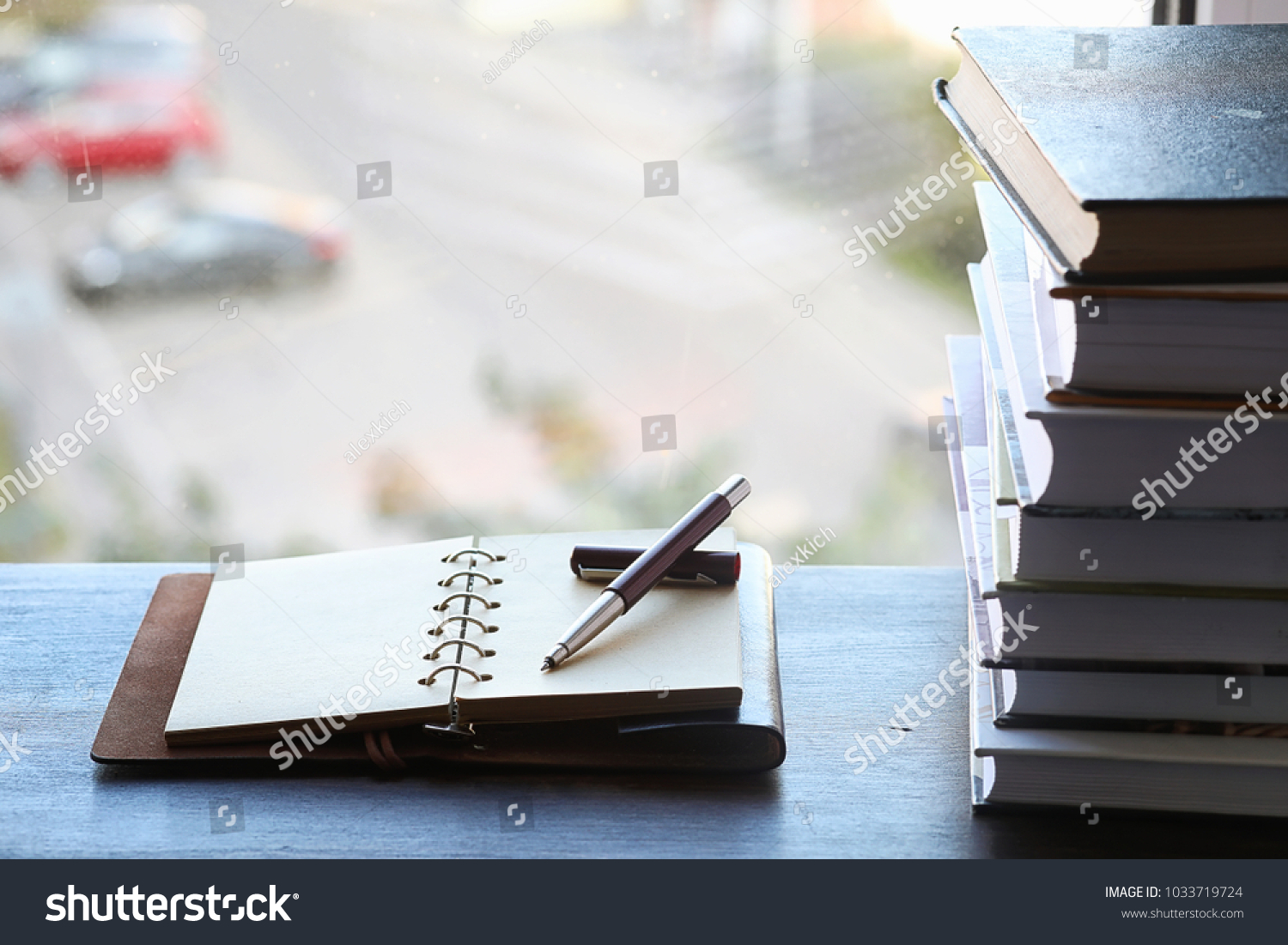 A stack of textbooks on the windowsill and writing utensils #1033719724