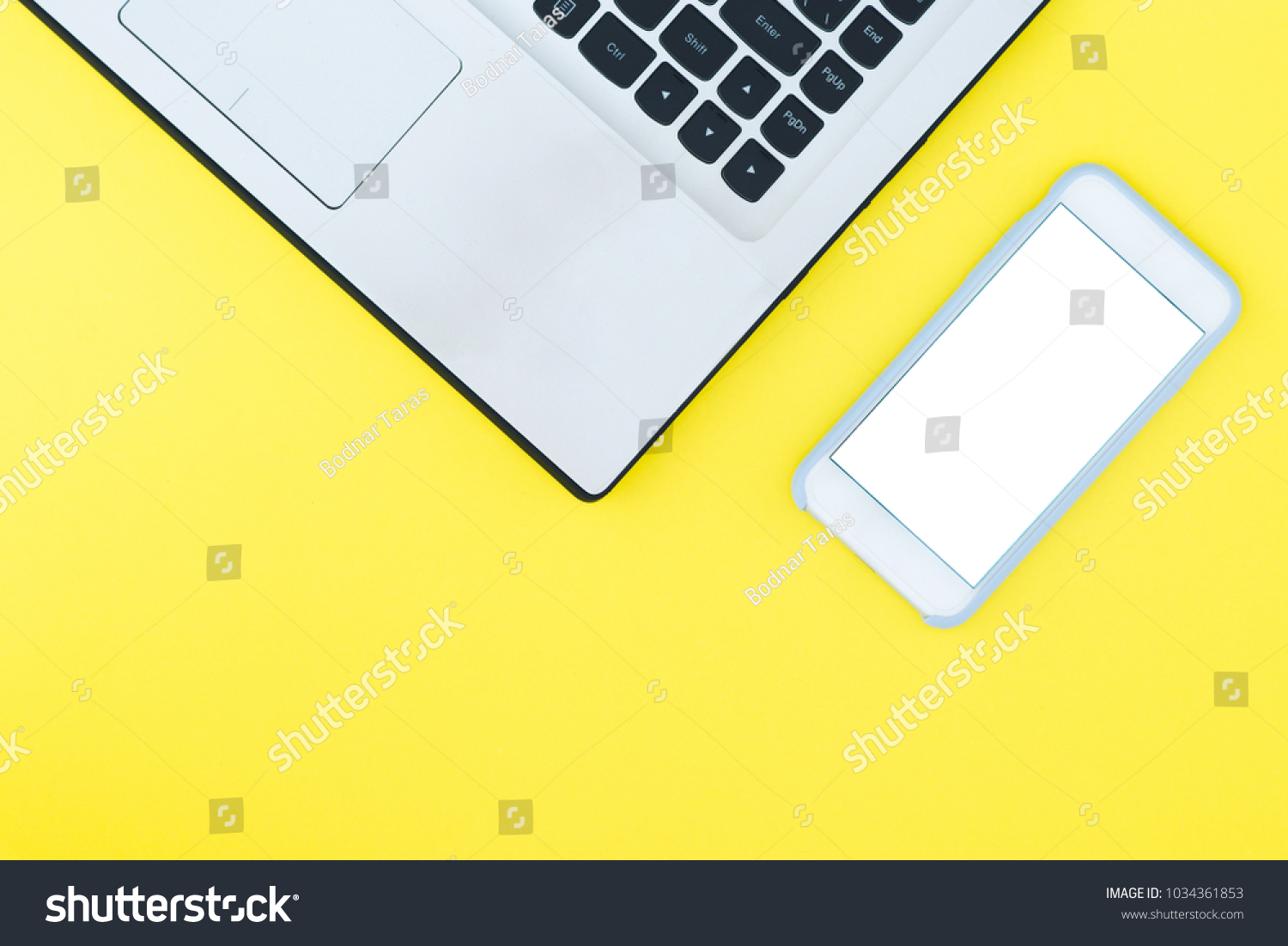 A laptop and a smartphone with a white screen on a yellow background. Minimalistic working space with a place for text. Flat Layout Layout. #1034361853