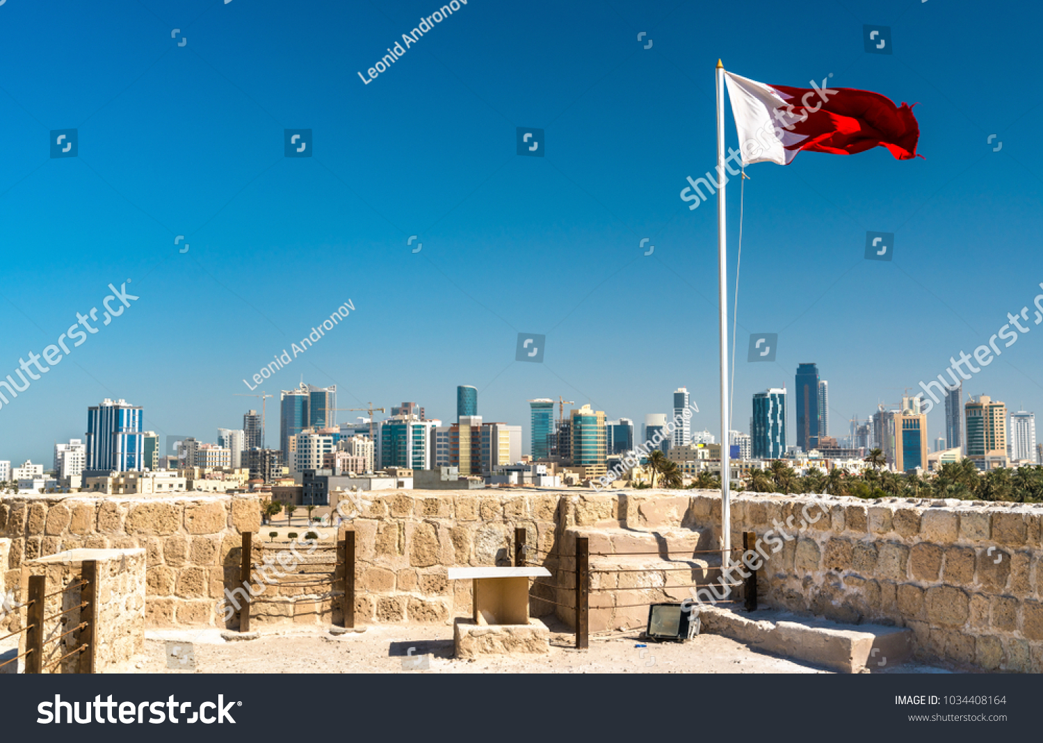 Bahrain Flag with skyline of Manama at Bahrain Fort. A UNESCO World Heritage Site in the Middle East #1034408164