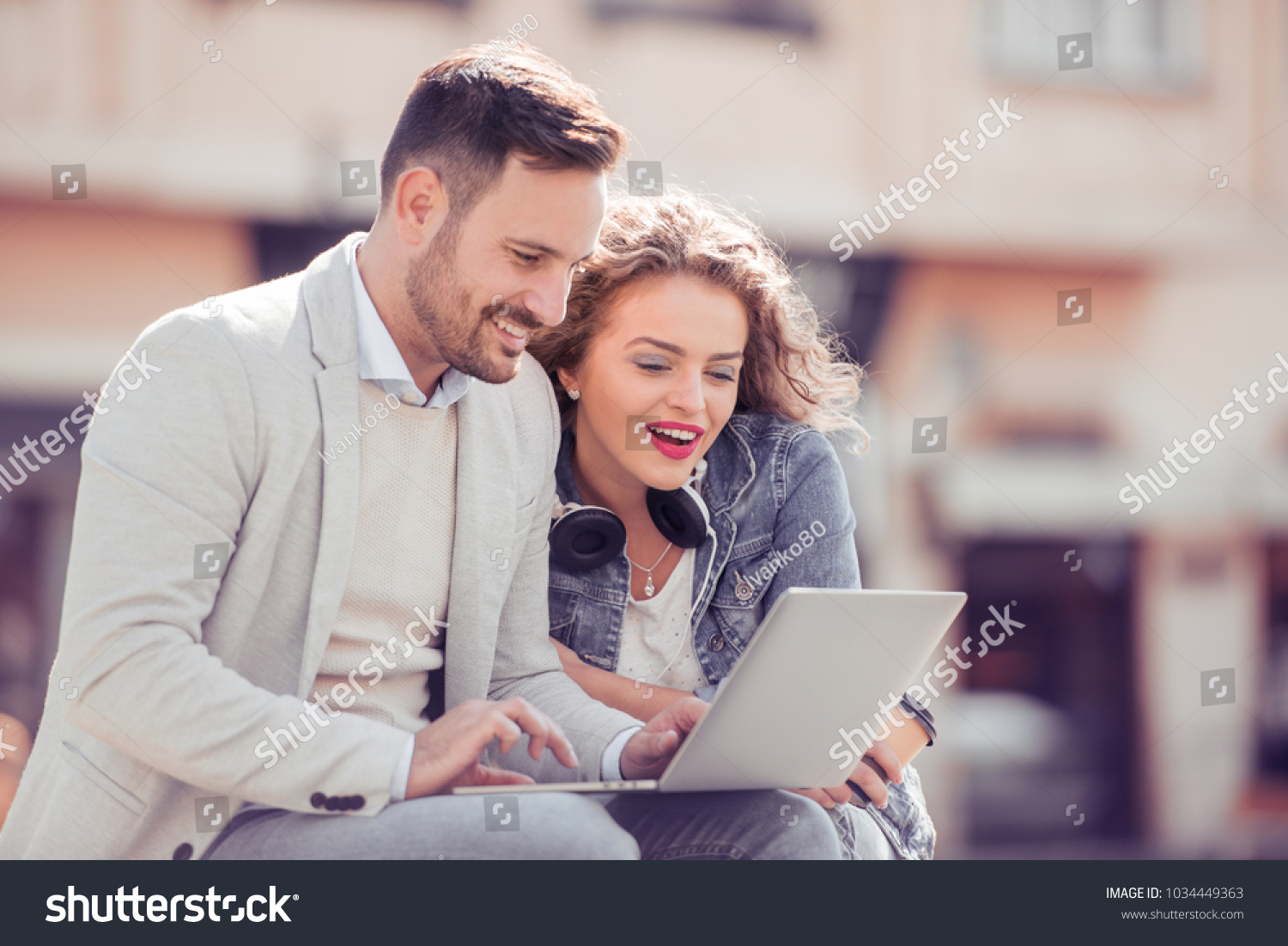 Young couple using a laptop outdoors and looking happy. #1034449363