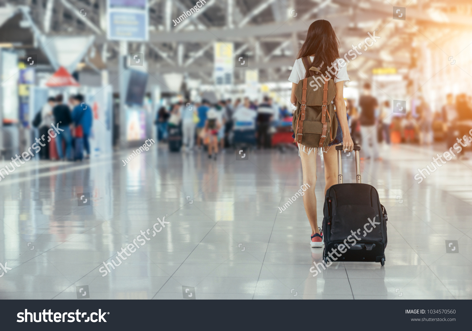 Asian teenage girl is using a smartphone to check flight at the international airport to travel on weekends. #1034570560