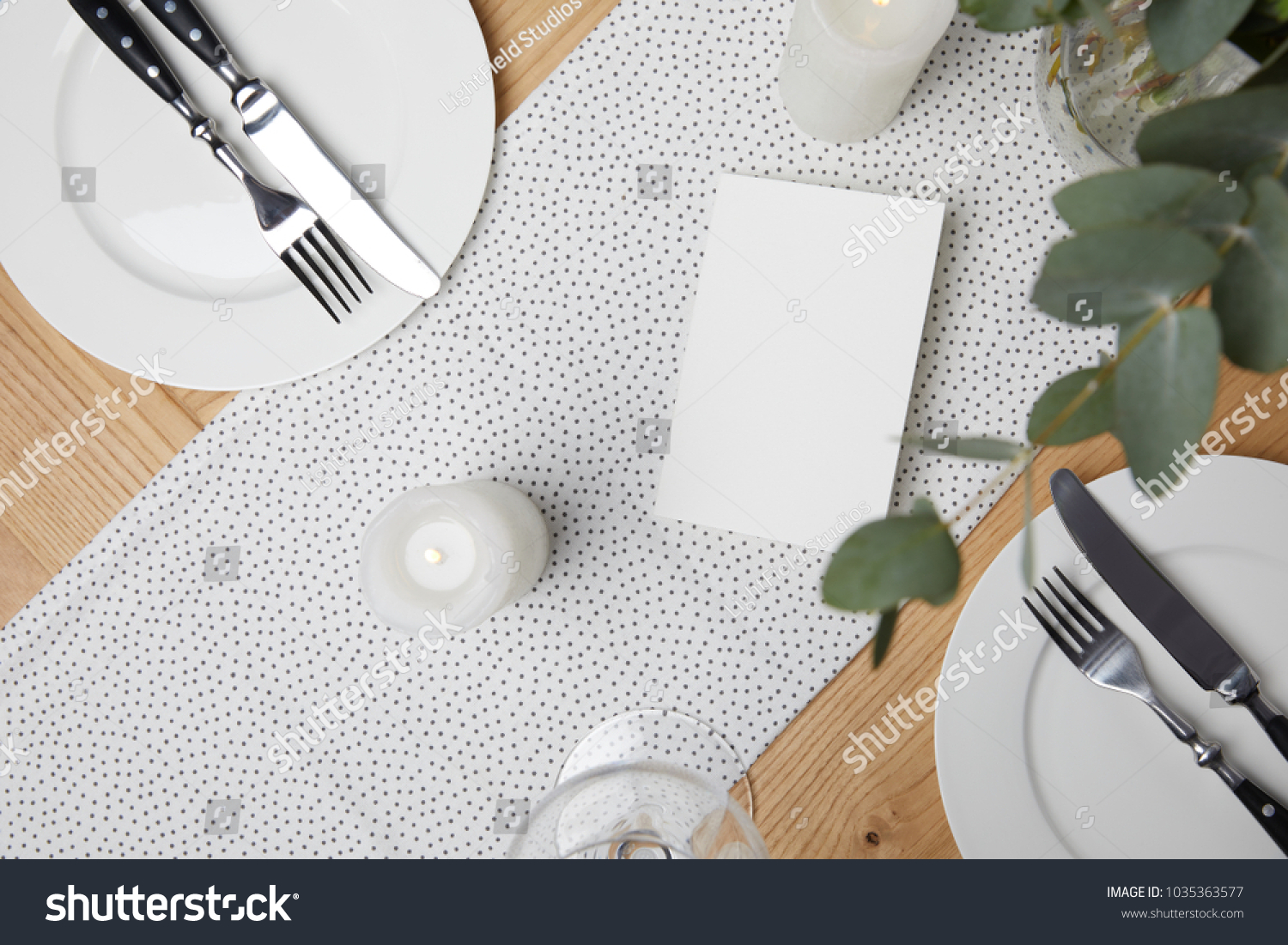 Festive table with cutlery on plates on table with candles #1035363577