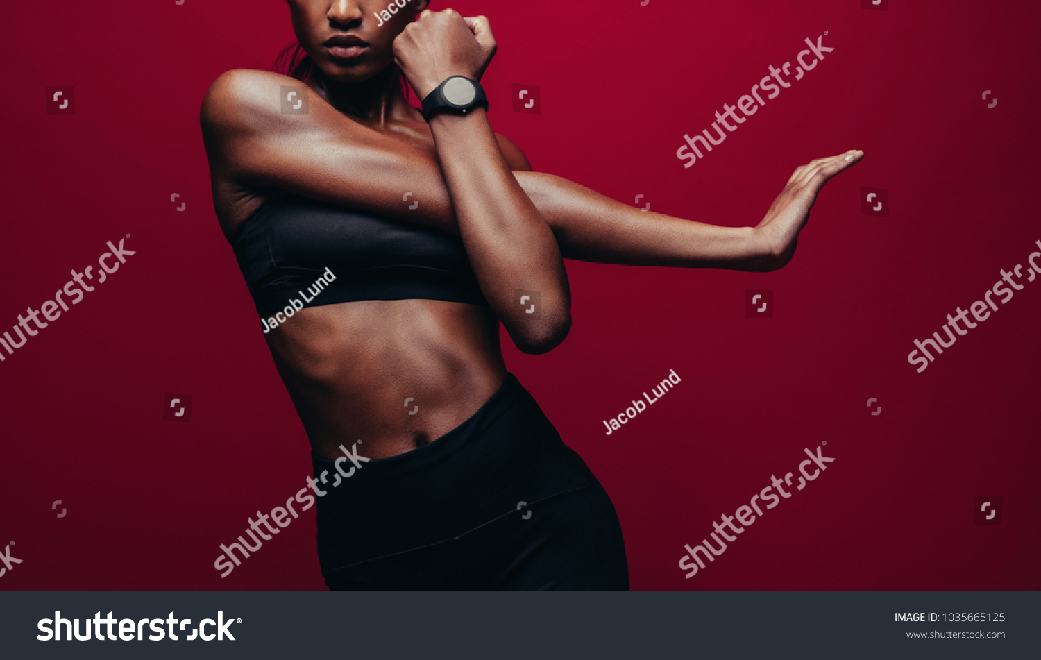 Cropped shot of woman stretching her arms. Female doing warmup stretching workout on red background. #1035665125