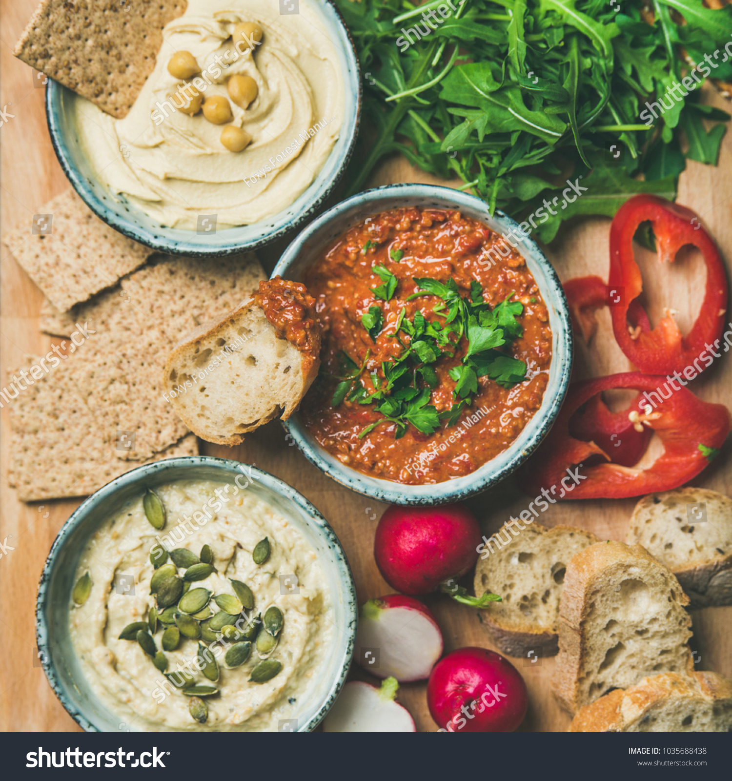 Vegan snack board. Flat-lay of various Vegetarian dips hummus, babaganush and muhammara with crackers, bread and fresh vegetables, top view, square crop. Clean eating, healthy, dieting food concept #1035688438
