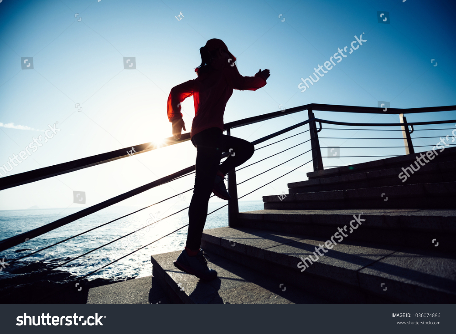sporty fitness female runner running upstairs on coast trail #1036074886