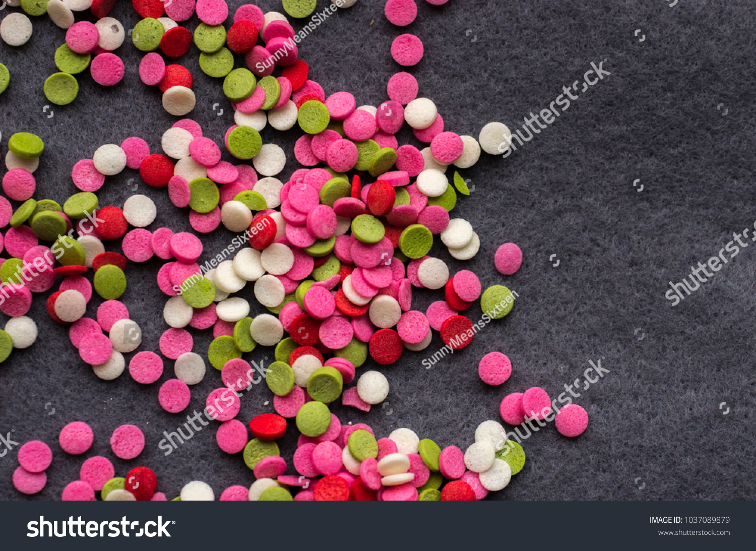 Multicolored sprinkles for a cake in form of circle on a gray wool background #1037089879