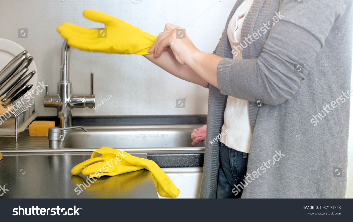 Closeup image of young housewife in yellow protective gloves on kitchen #1037171353