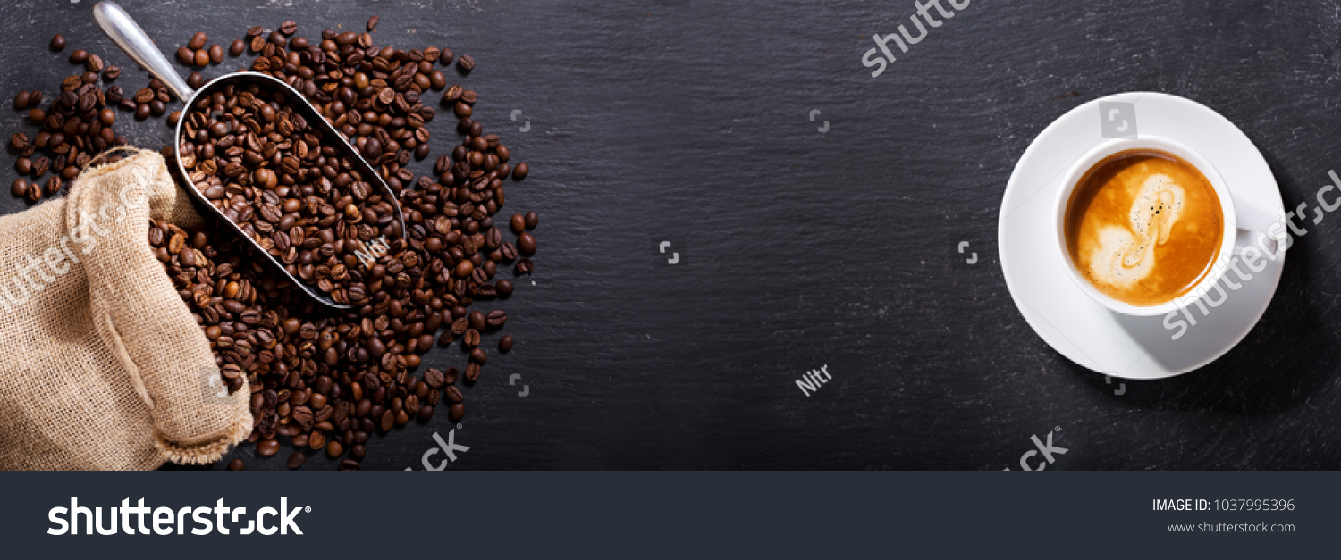 cup of coffee and coffee beans in a sack on dark background, top view #1037995396