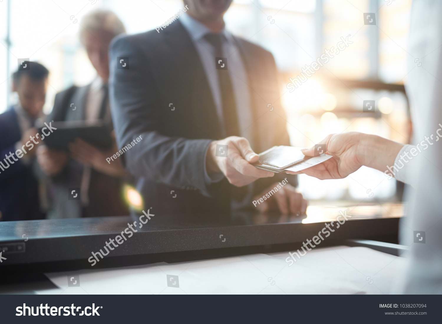 Businessman taking back his passport and ticket from hand of administrator after check-in #1038207094