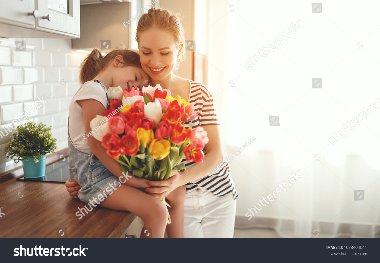 happy mother's day! child daughter congratulates mother and gives a bouquet of flowers to tulips #1038404041