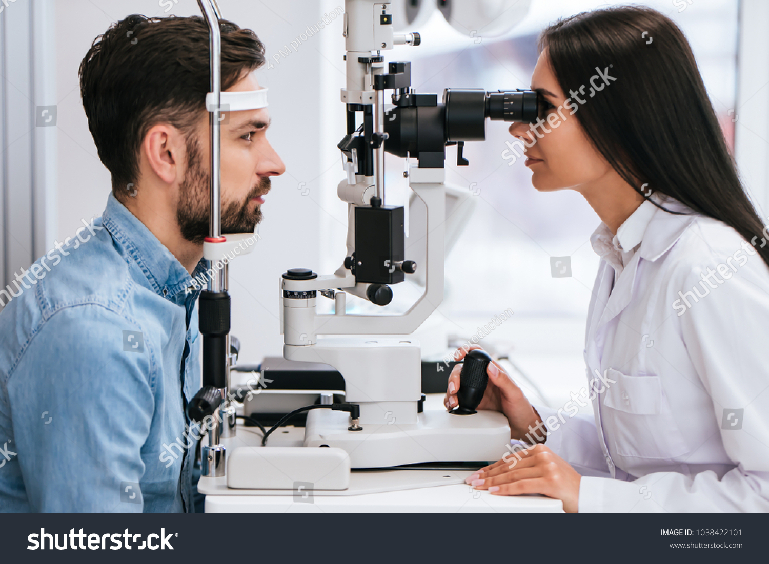 Attractive female doctor  ophthalmologist is checking the eye vision of handsome young man in modern clinic. Doctor and patient in ophthalmology clinic. #1038422101