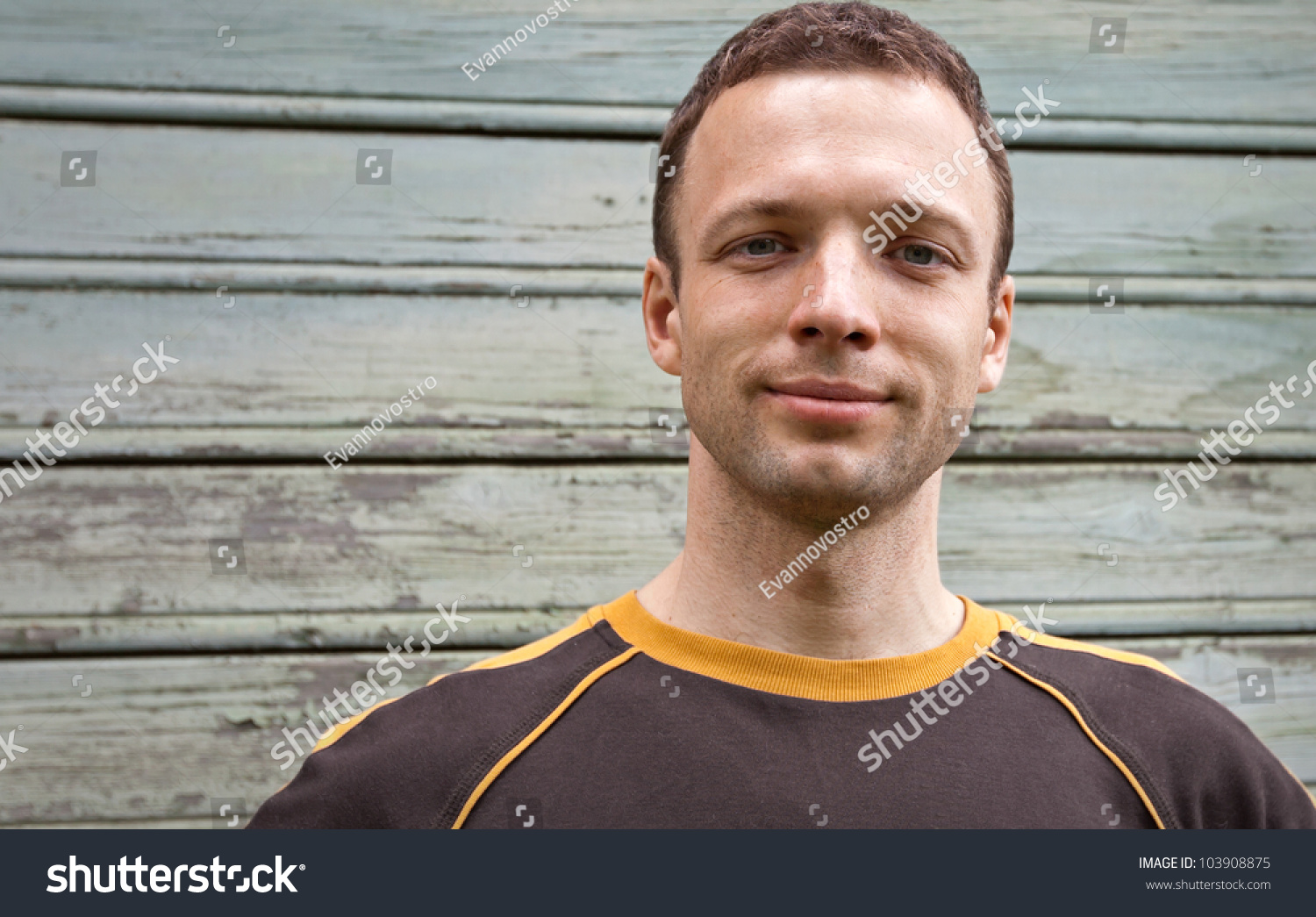 Closeup portrait of young man slightly smiling over old wooden wall #103908875