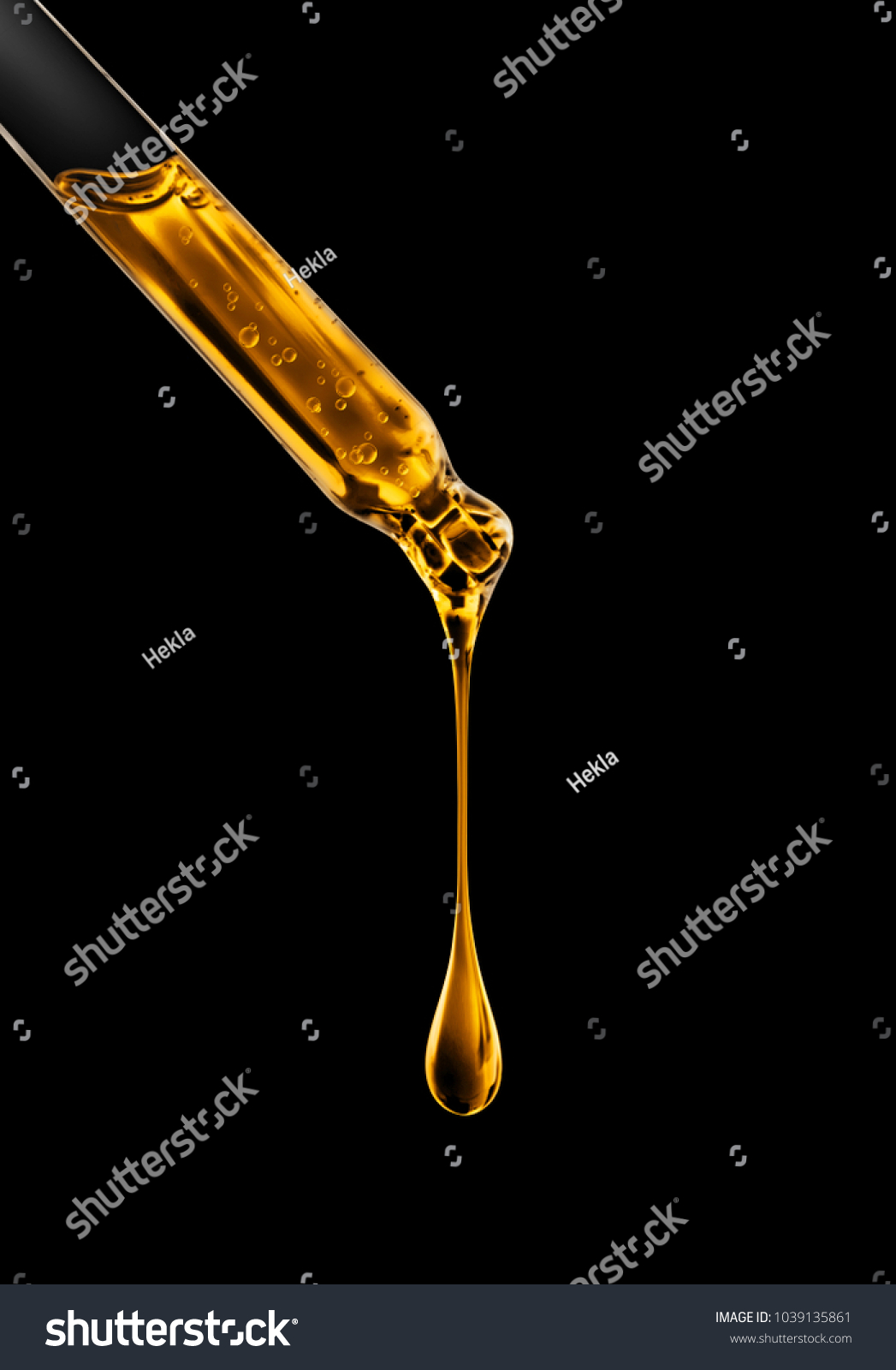 Cosmetic pipette with oily drop closeup on black background #1039135861