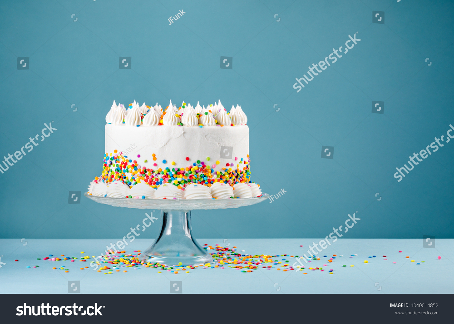 White Birthday cake with colorful Sprinkles over a blue background. #1040014852