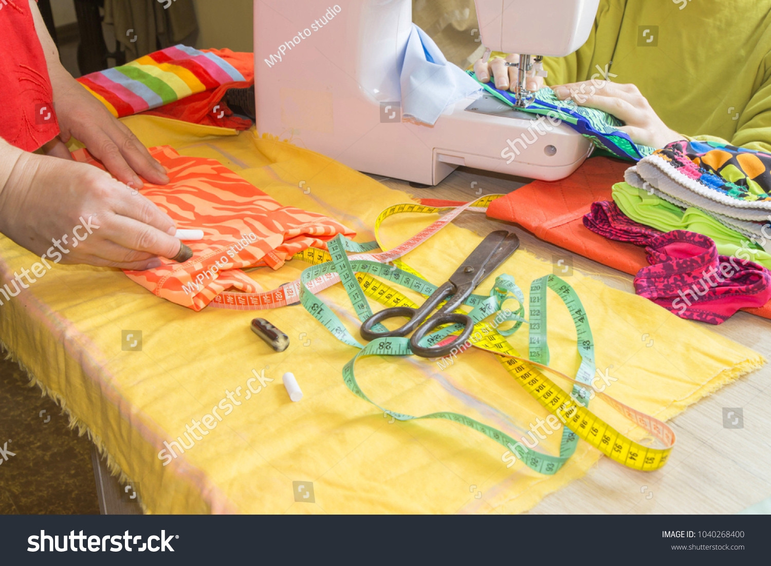 Female fashion designer working at studio with pattern cuttings and sketches. Garment industry, tailoring concept. woman seamstress sitting and sews on sewing machine #1040268400