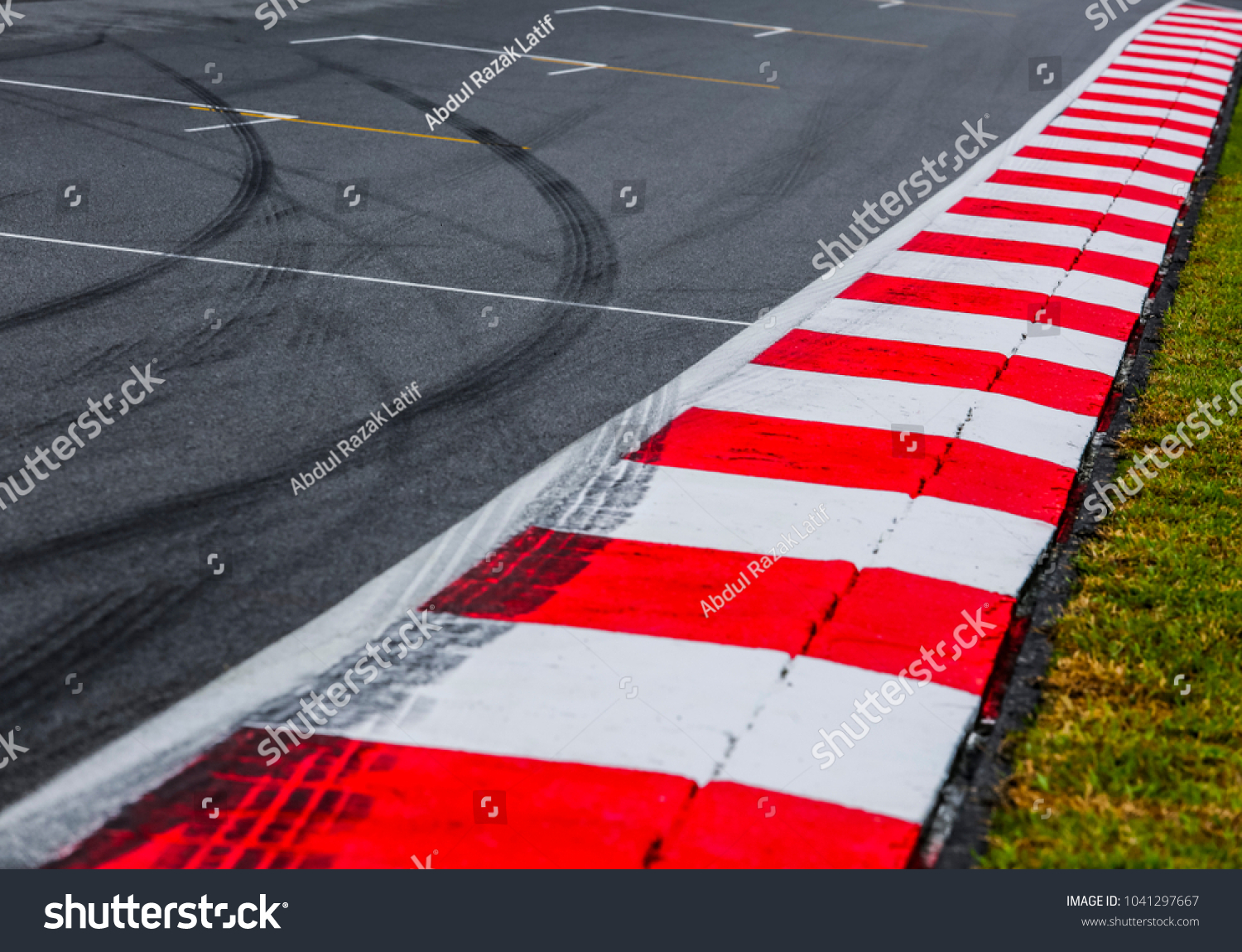Asphalt red and white kerb of a race track detail with tire marks. Motorsports racing circuit close up.  #1041297667