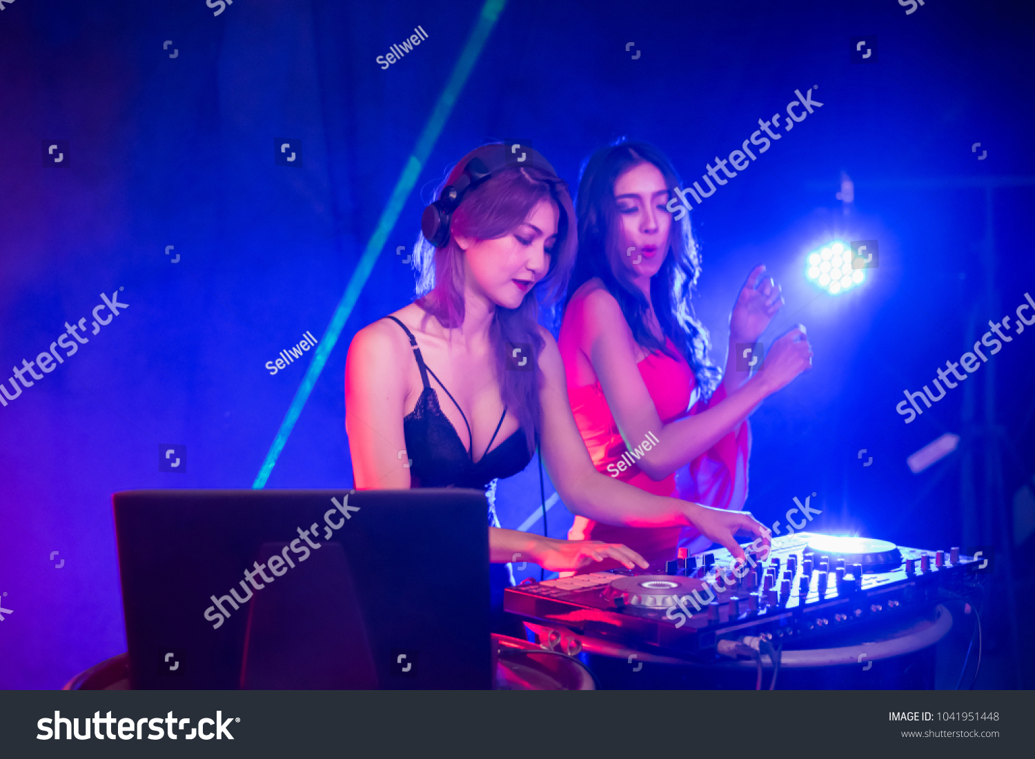 Music Concepts. DJ is rhythm music with Controller and mixer. DJ is playing the song at the party. Young are adjusting the music with the controller. The fun of music and light colors. #1041951448