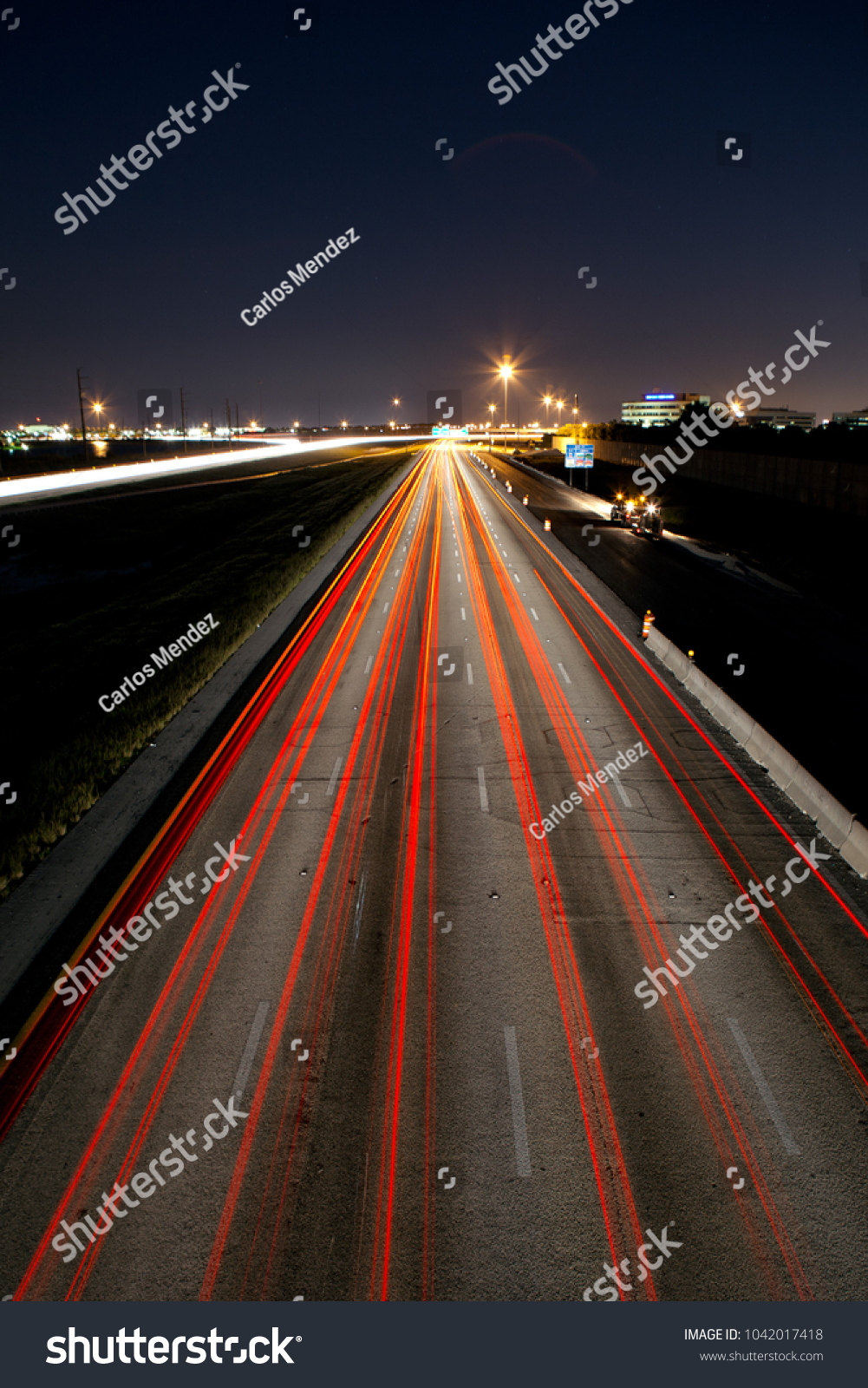 Long exposure of cars traveling through major highway, leaving light trails and conveying motion and progress.  #1042017418