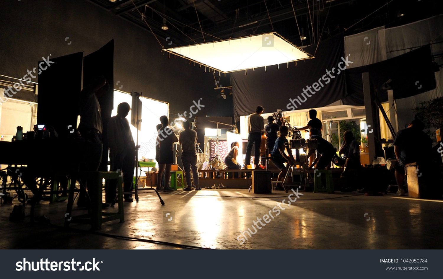 Behind the scenes or the making of film video production and movie crew team working in silhouette of camera and equipment set in studio.  #1042050784
