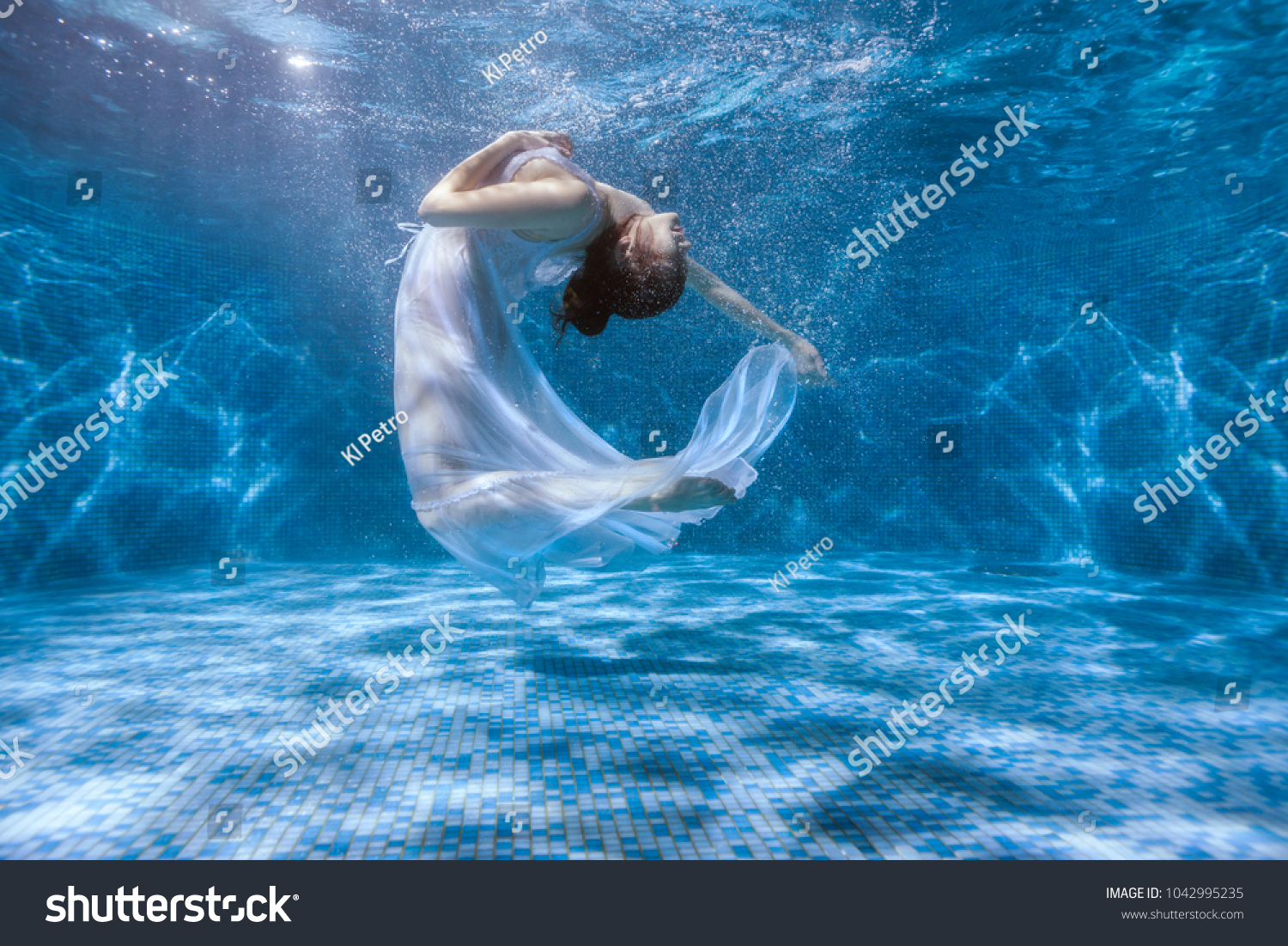 Girl shows the performance under the water, she dances in a white dress. #1042995235