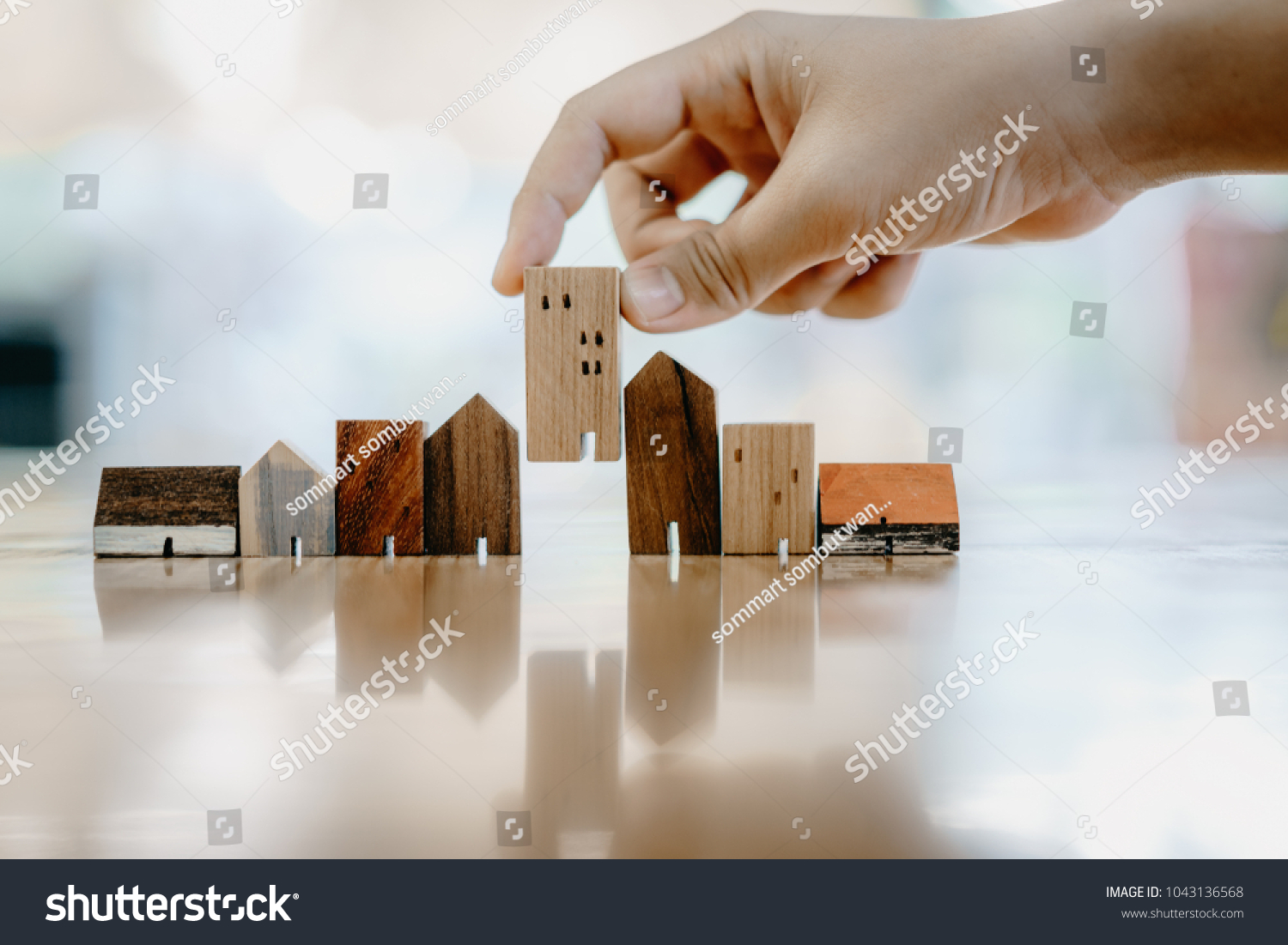 Hand choosing mini wood house model from model and row of coin money on wood table, selective focus, Planning to buy property. Choose what's the best. A symbol for construction ,ecology, loan concepts #1043136568
