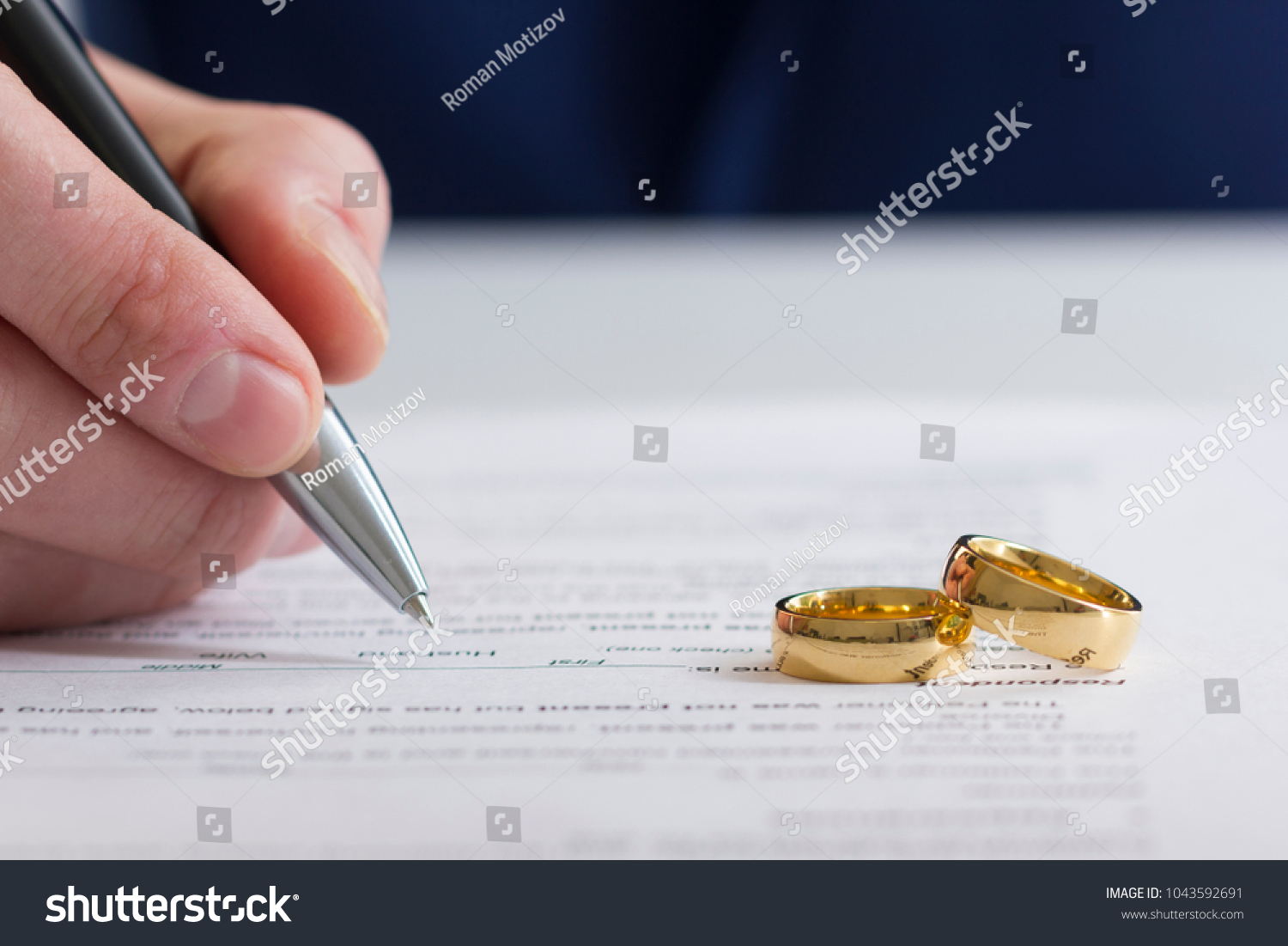 Hands of wife, husband signing decree of divorce, dissolution, canceling marriage, legal separation documents, filing divorce papers or premarital agreement prepared by lawyer. Wedding ring #1043592691
