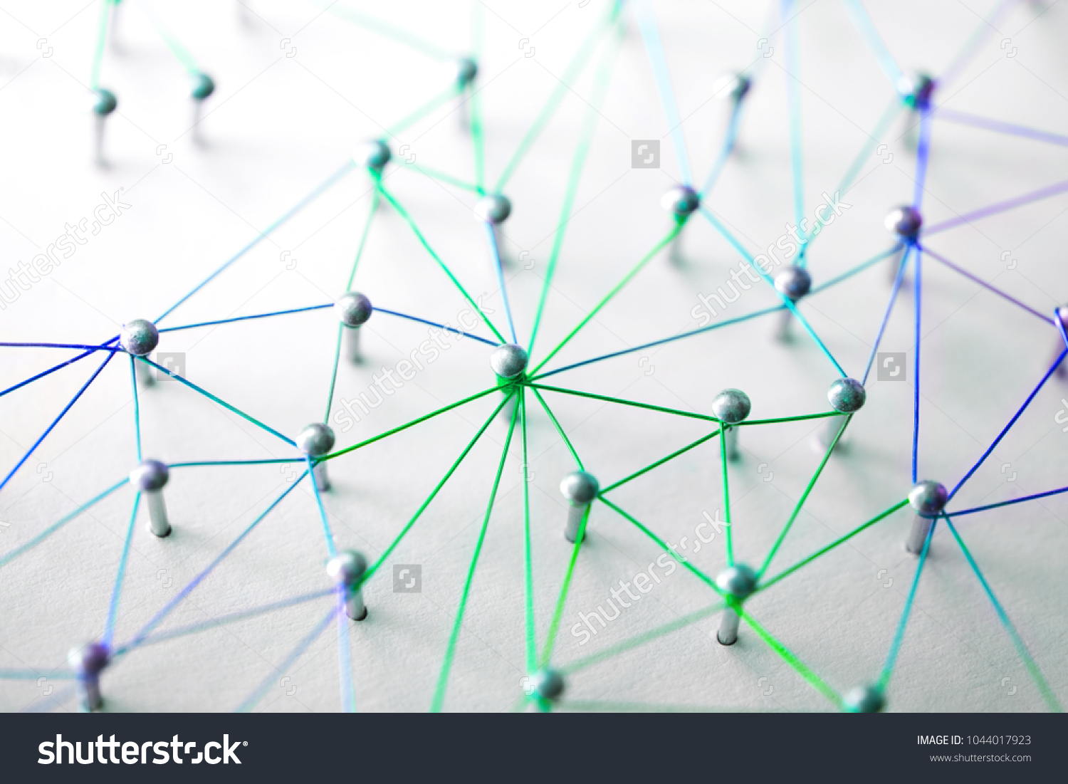 Linking entities. Networking, social media, SNS, internet communication abstract. devices or people connected to a network. Web of green, blue and purple wires on white background. Shallow DOF. #1044017923