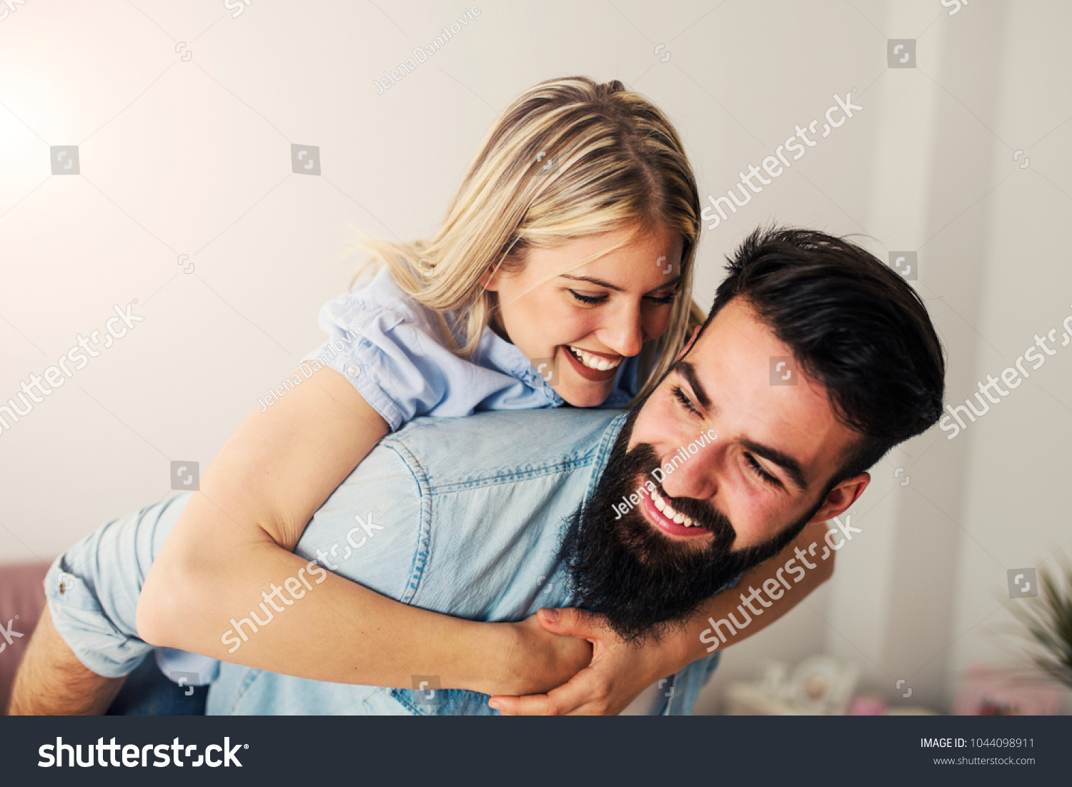 Modern young bearded man carrying his laughing girlfriend around #1044098911