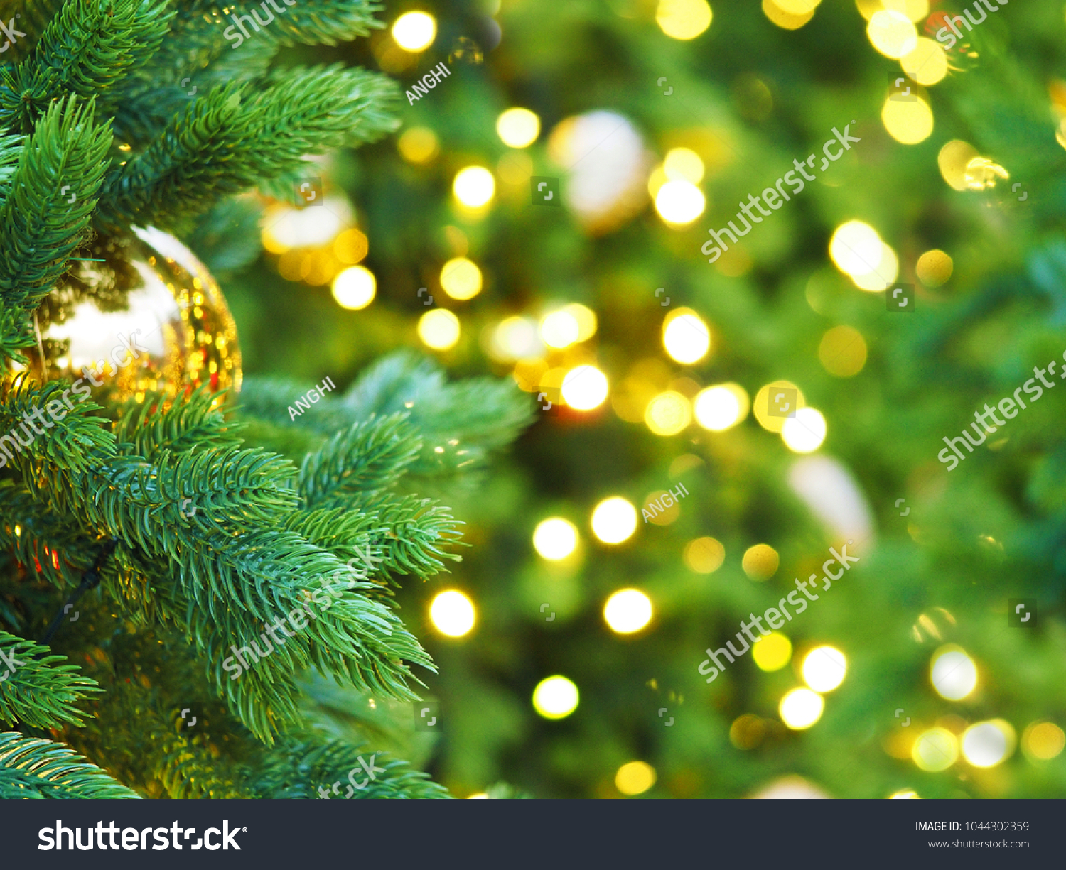 Christmas tree with holiday golden decorations and lights. Space for text. Festive New Year background, selective focus, Christmas fir tree garlands, balls and toys. Illumination #1044302359