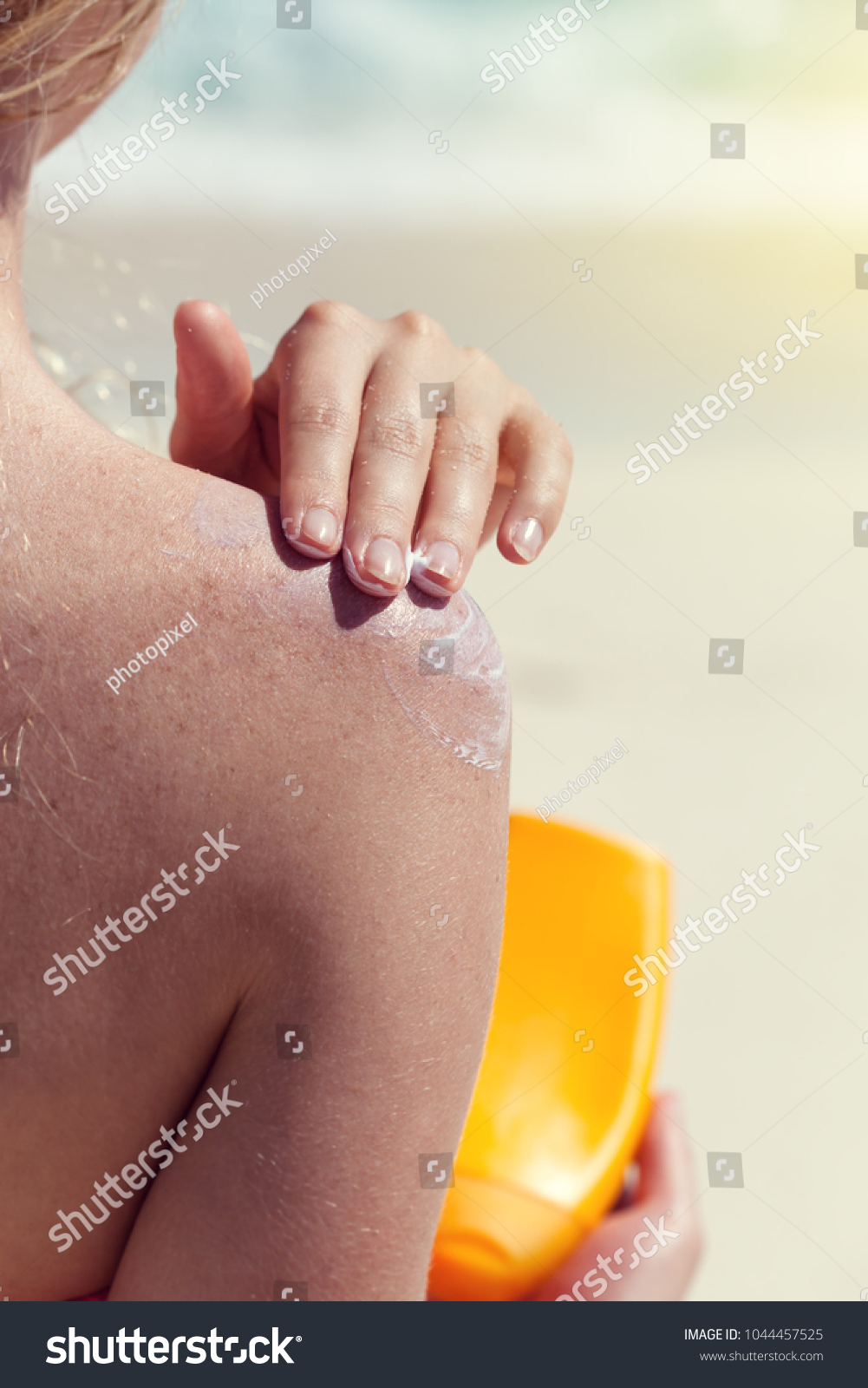 Woman apply sunscreen lotion on shoulder skin for healthy suntanning on tropical vacation, beauty concept #1044457525