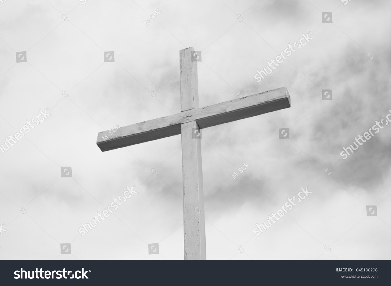Wooden cross as religious symbol of Christianity and Christian religion - grey cloudy sky in the background. Minimalist symbolism. Low contrast #1045190296