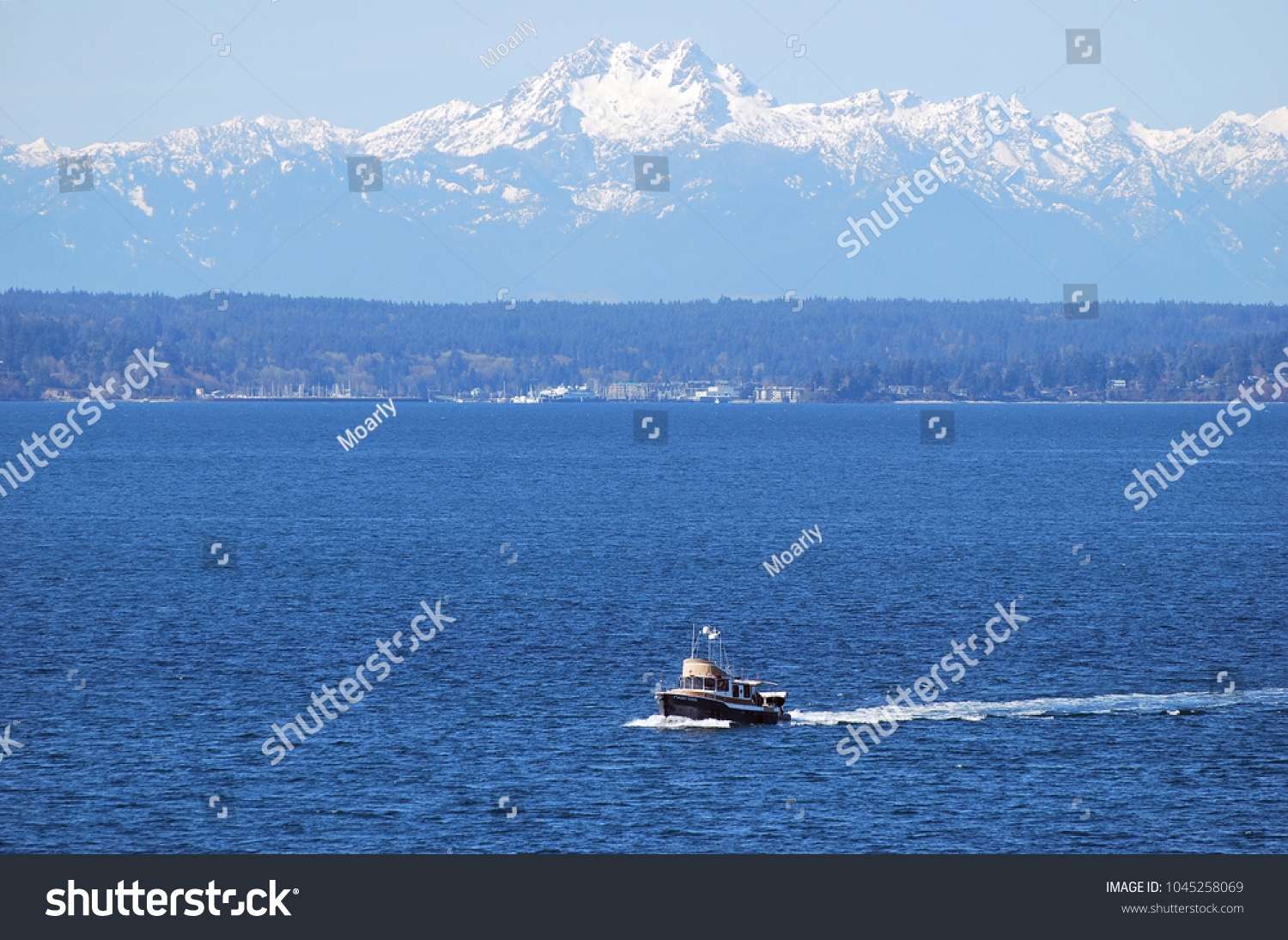 Boat driving along in front of Olympic Mountains on Elliott Bay in Seattle #1045258069
