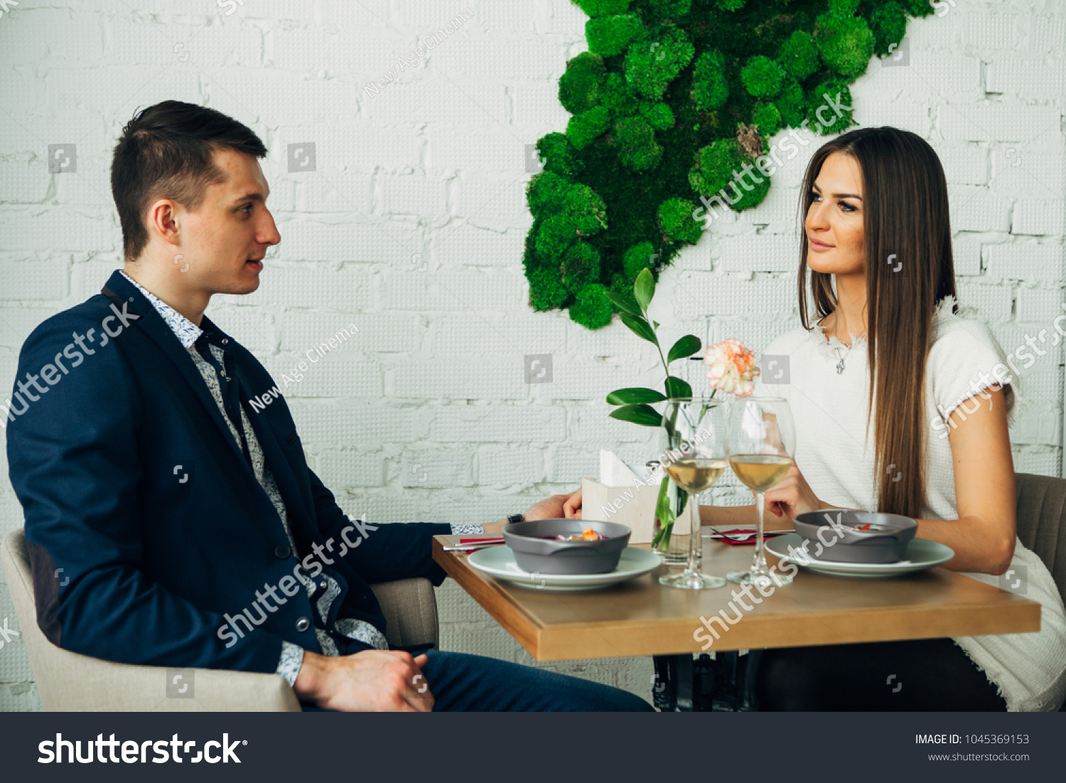smiling couple having dinner and drinking white wine at date in restaurant #1045369153
