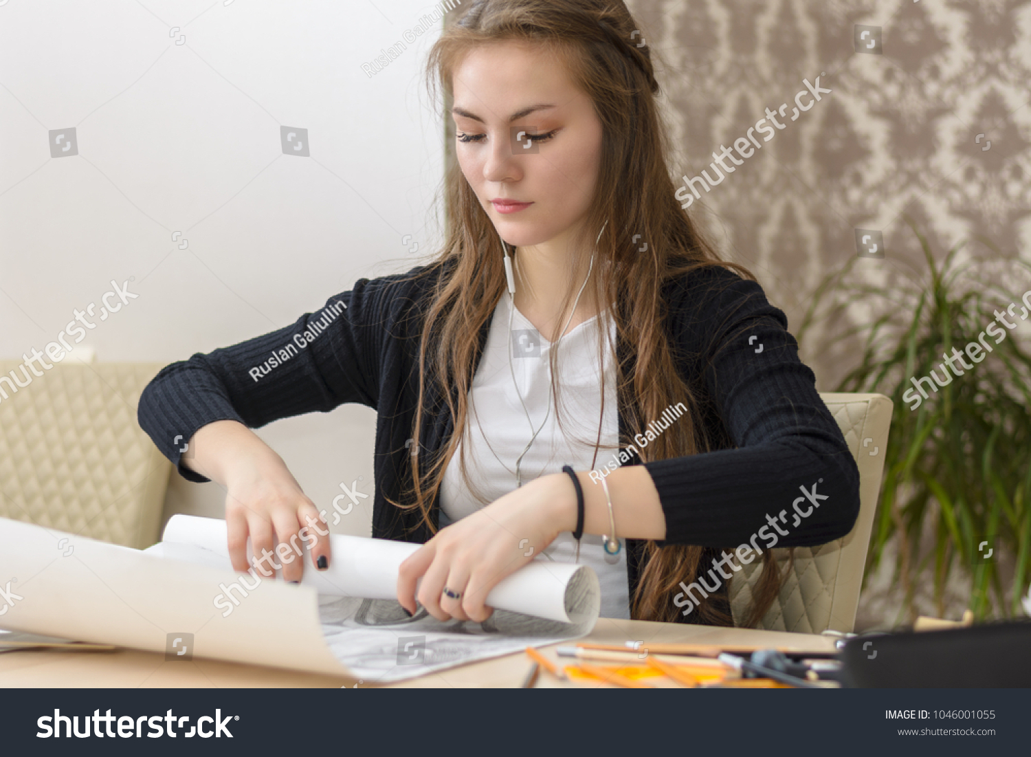 Frontal portrait of a young female student is engaged at the table draws sketches, sketches, plans, architecture. training and practice. #1046001055