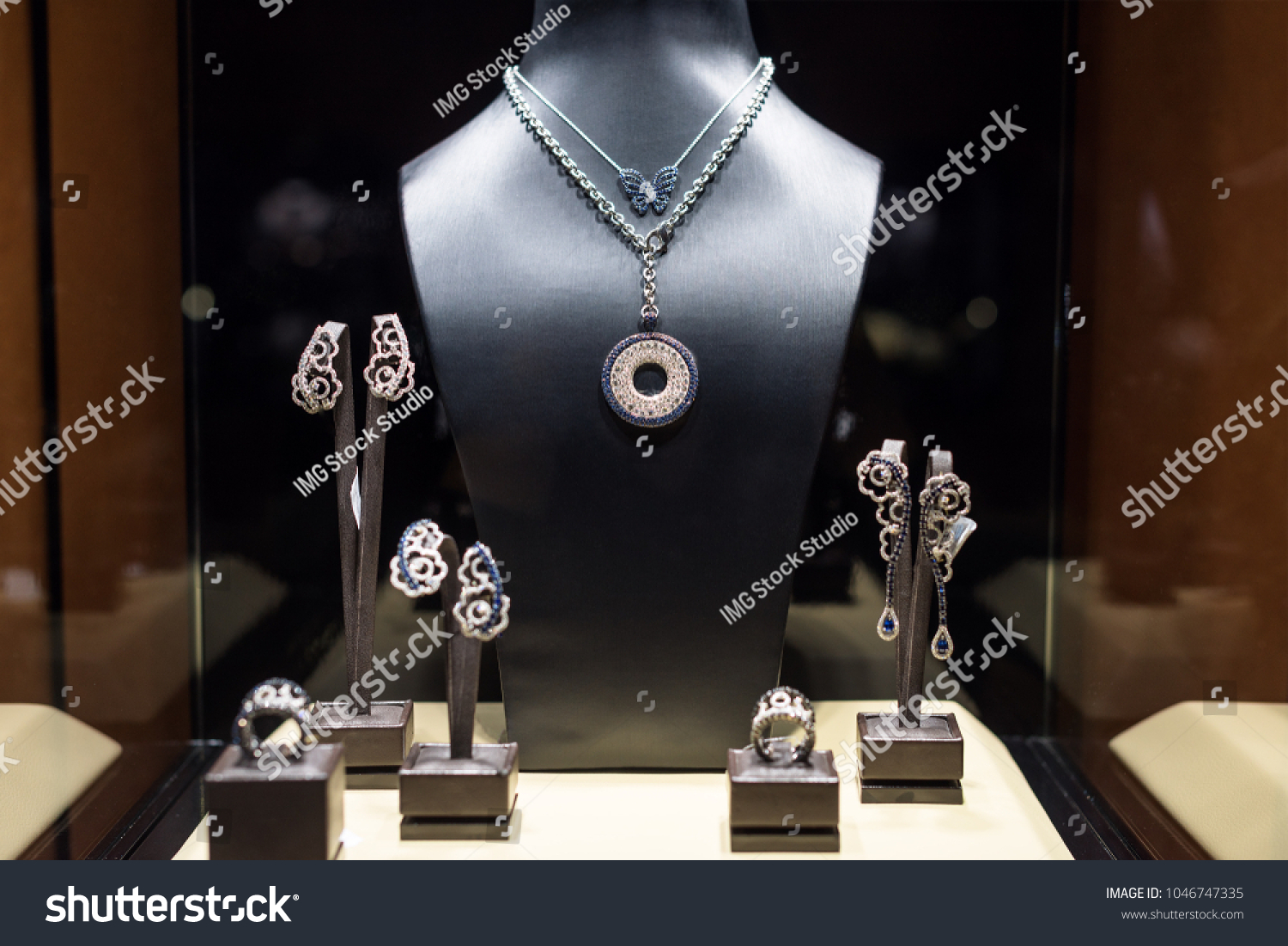 Variety of jewelry in store window. Rings, bracelets, earrings and necklaces on stands for sale. #1046747335