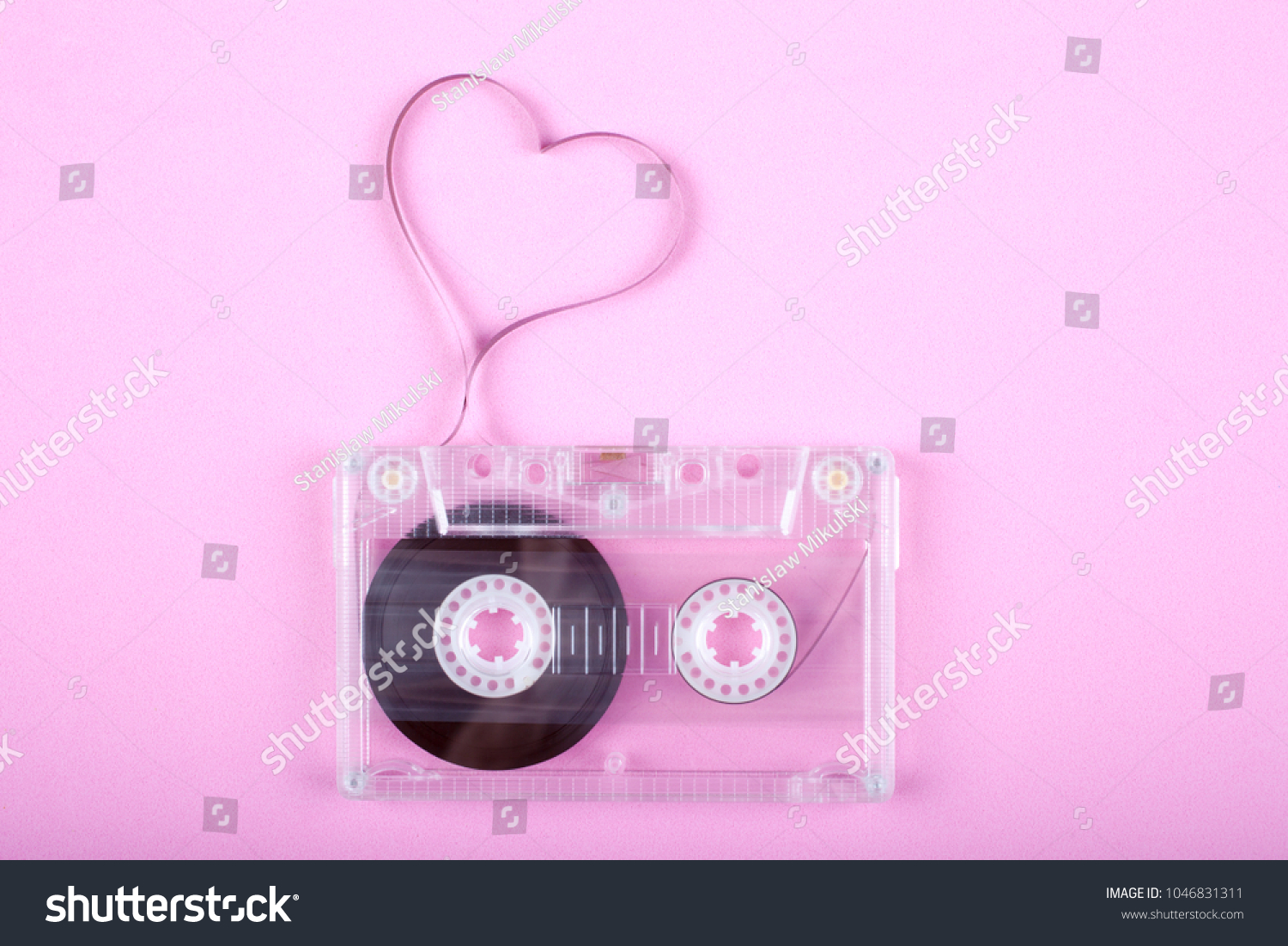 Film in a shape of heart from Compact Cassette. Love for music and songs. Pink background. #1046831311